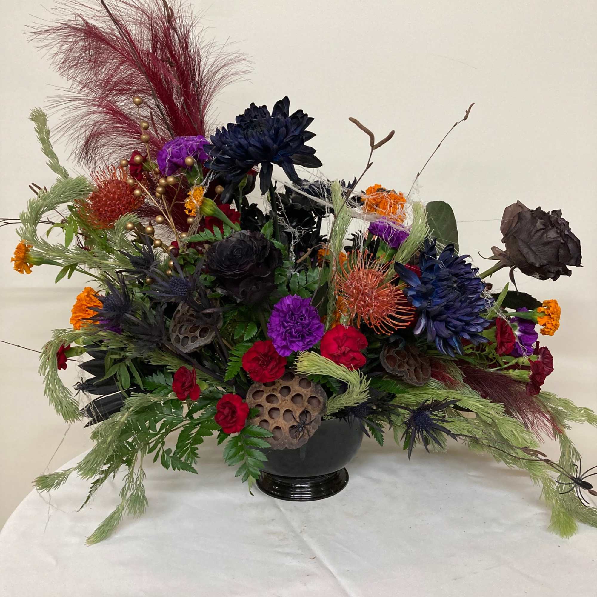Give a creepy. crawly, spooky arrangements mad with mums, carnations, roses, marigolds