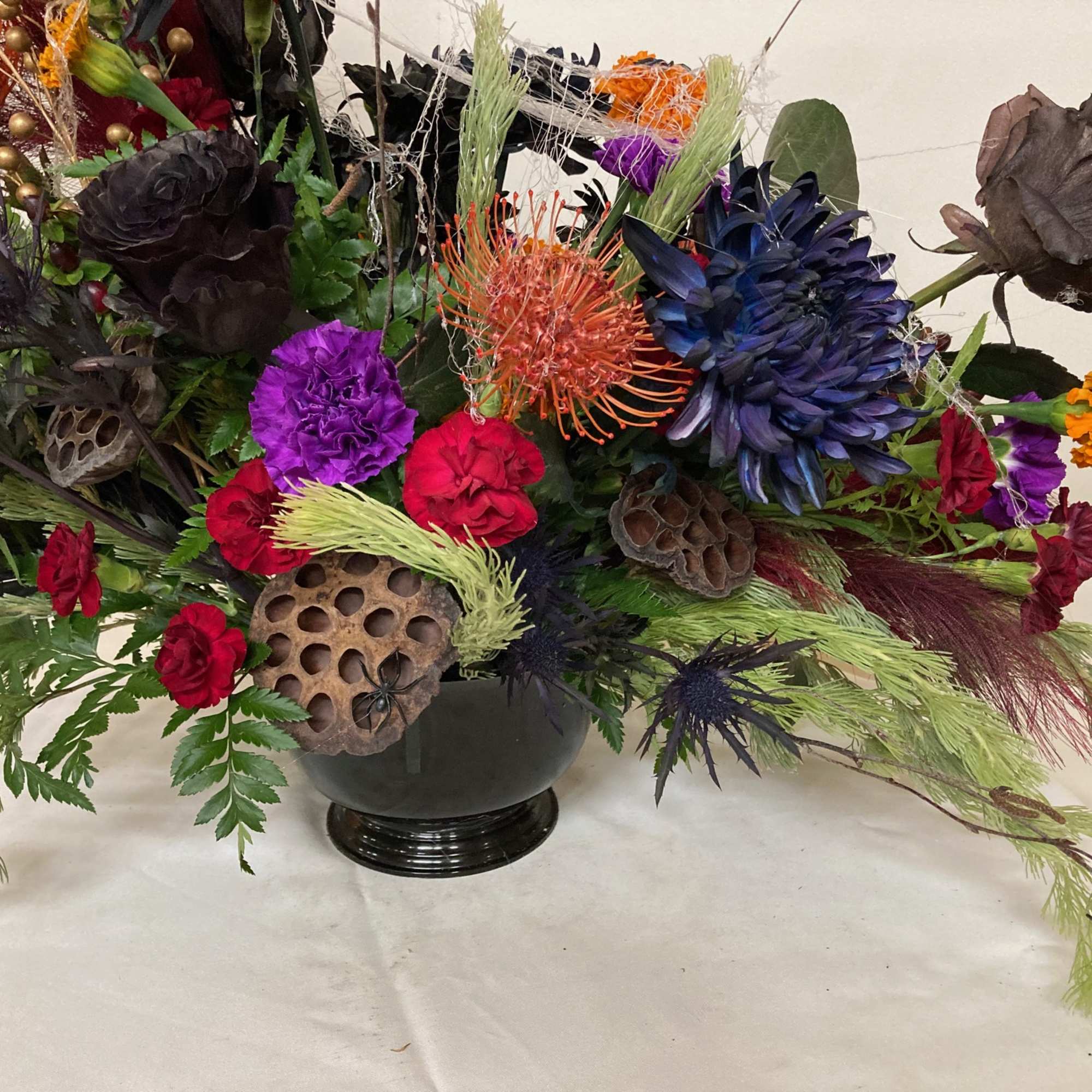 Give a creepy. crawly, spooky arrangements mad with mums, carnations, roses, marigolds