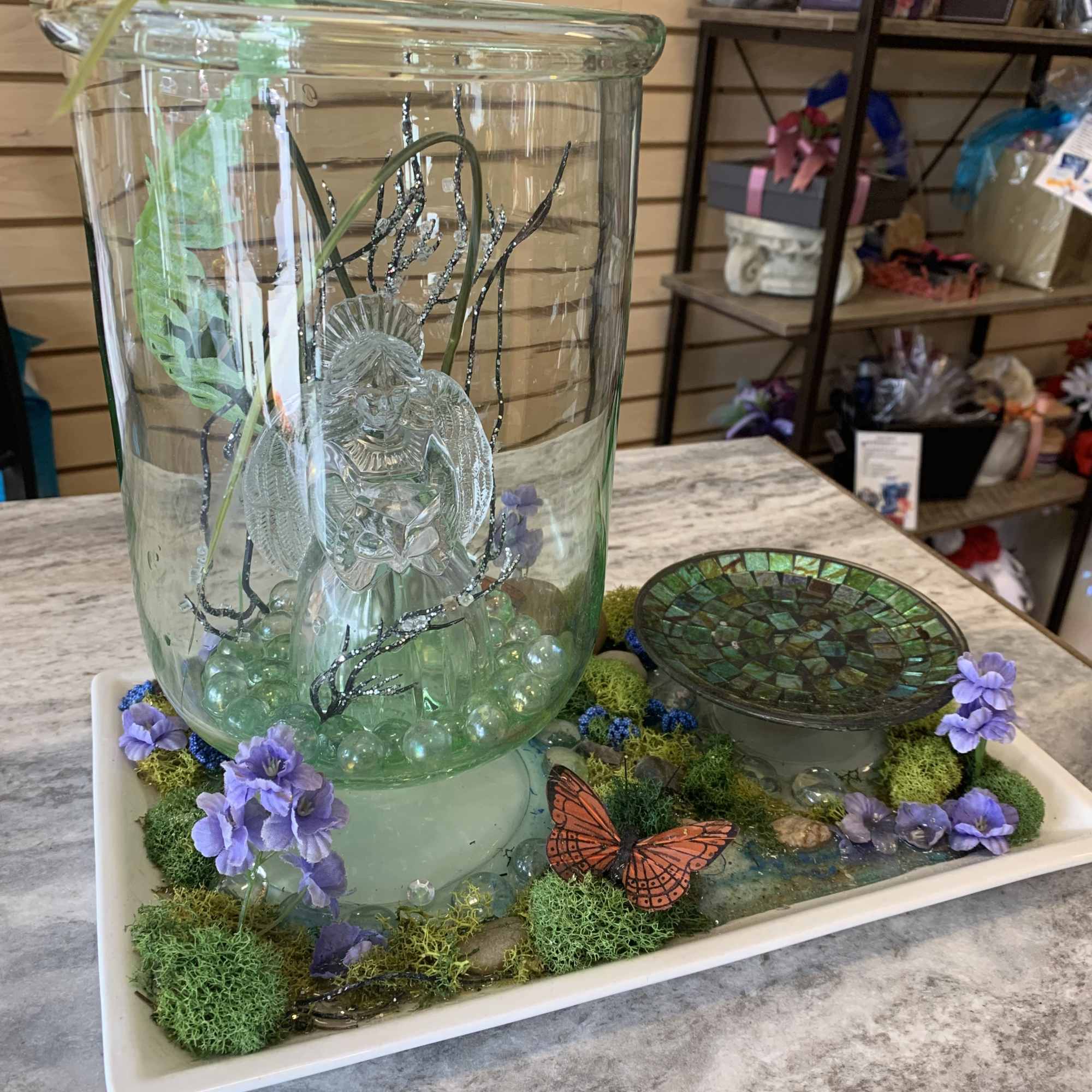 Glass vase with glass angel and butterflies and moss with lavender flowers Glass vase with glass angel and butterflies and moss with lavender flowers