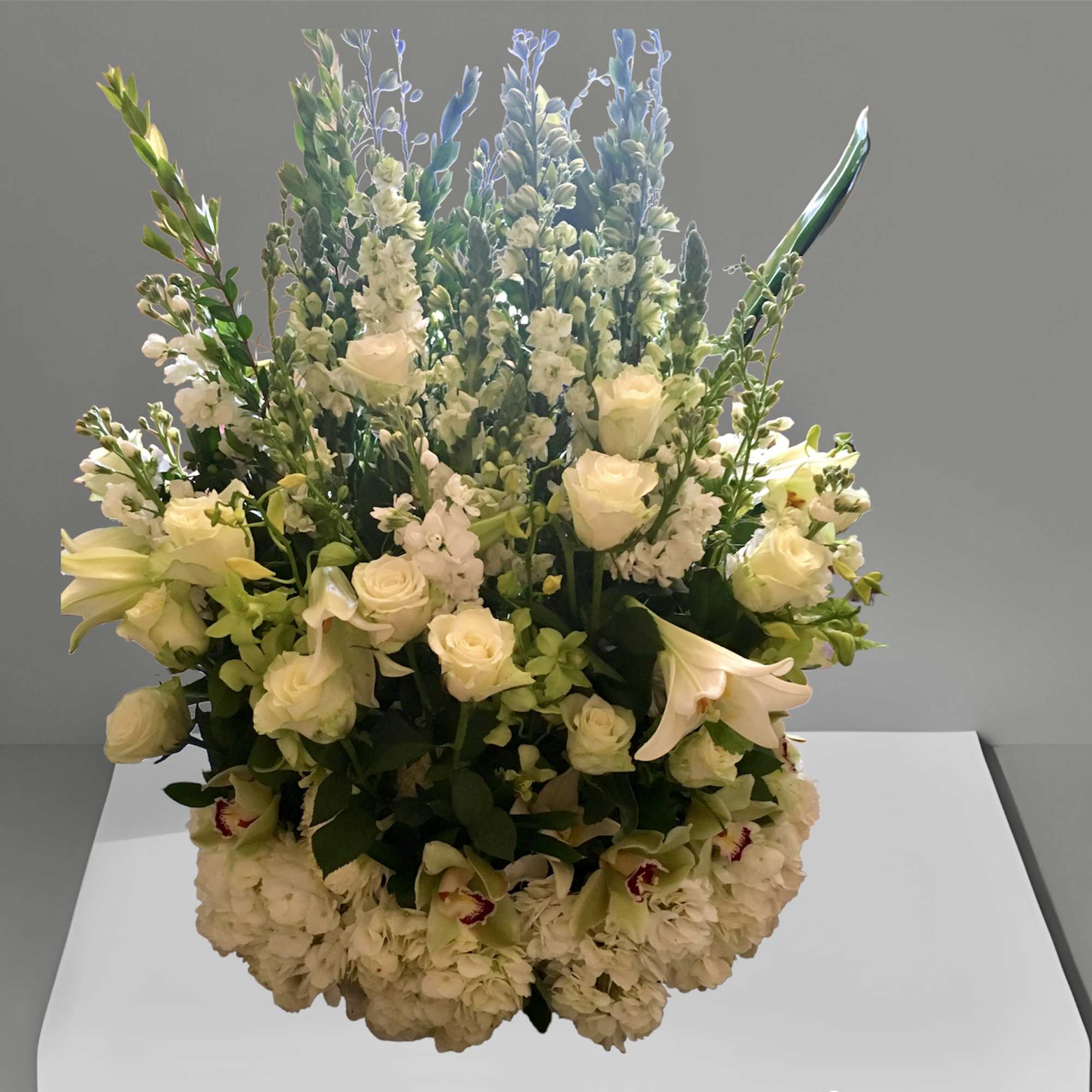Large arrangement of roses, lilies, orchids, larkspur, tall myrtle, and assorted white