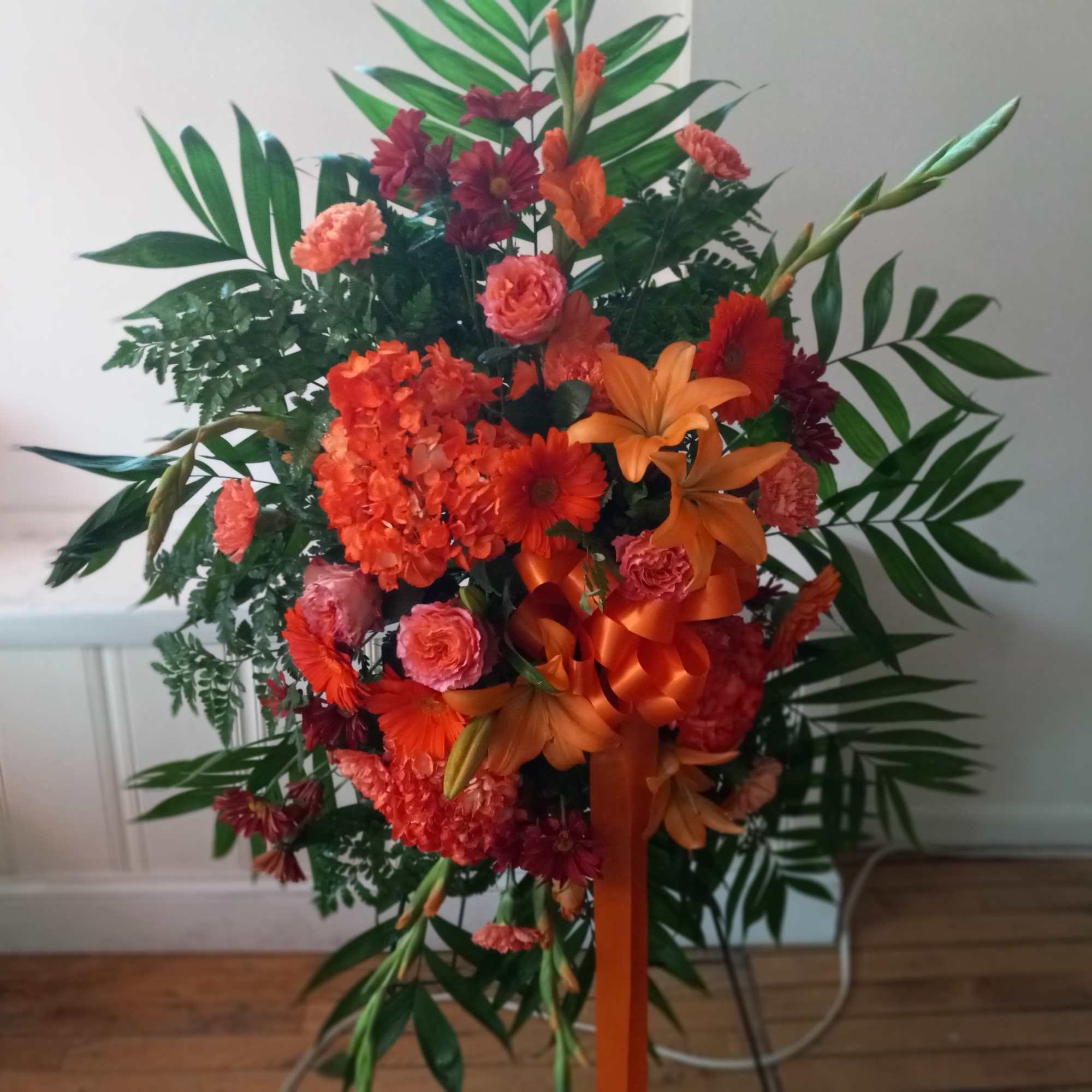 Bright orange colors funeral standing spray symbolizes deep sympathy  