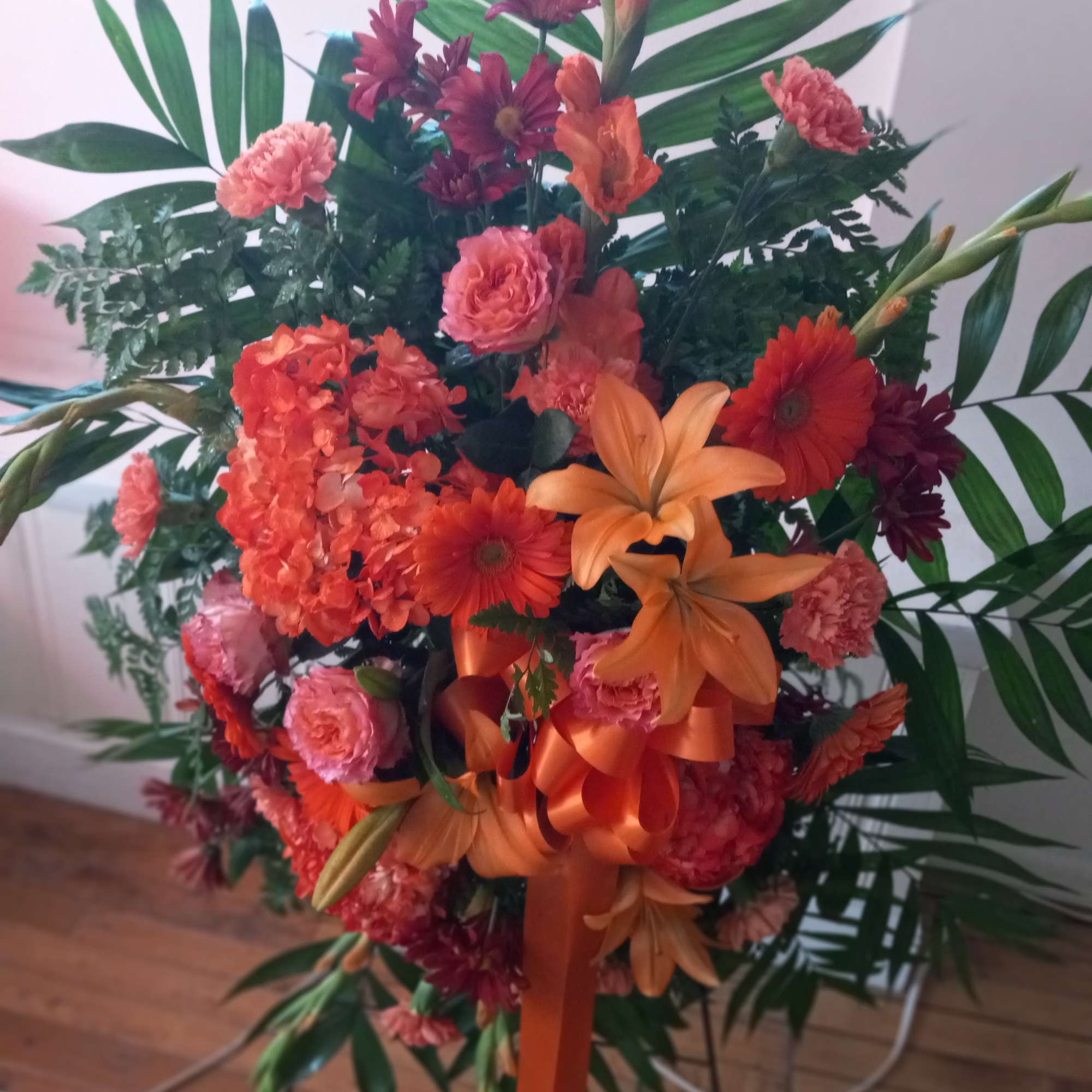 Bright orange colors funeral standing spray symbolizes deep sympathy  