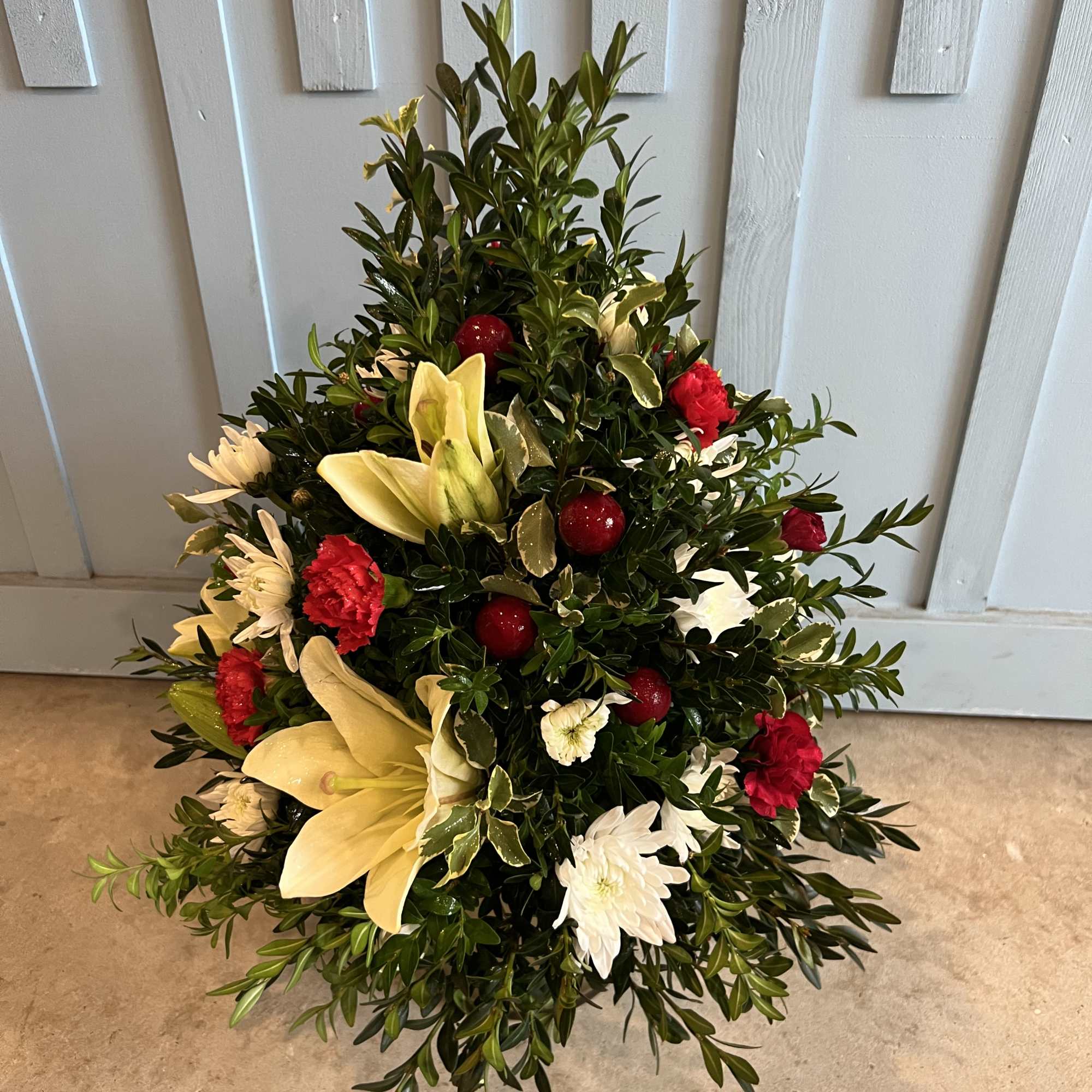 Christmas tree shaped arrangement with fresh greens and flowers. Approximately 12" to Christmas tree shaped arrangement with fresh greens and flowers. Approximately 12" to