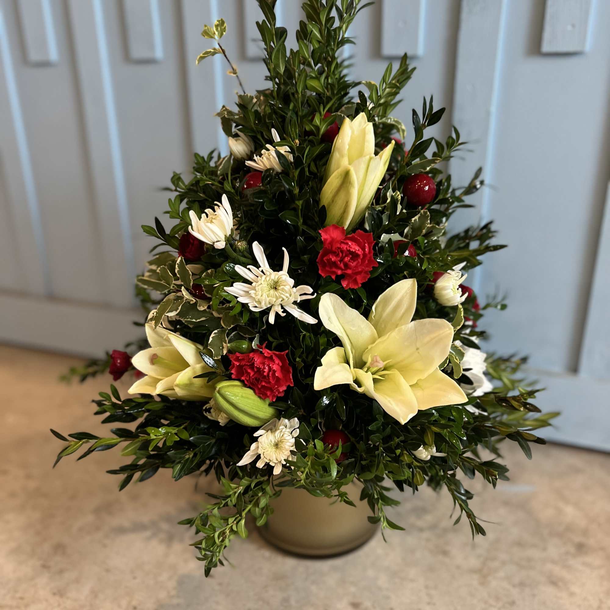 Christmas tree shaped arrangement with fresh greens and flowers. Approximately 12" to Christmas tree shaped arrangement with fresh greens and flowers. Approximately 12" to