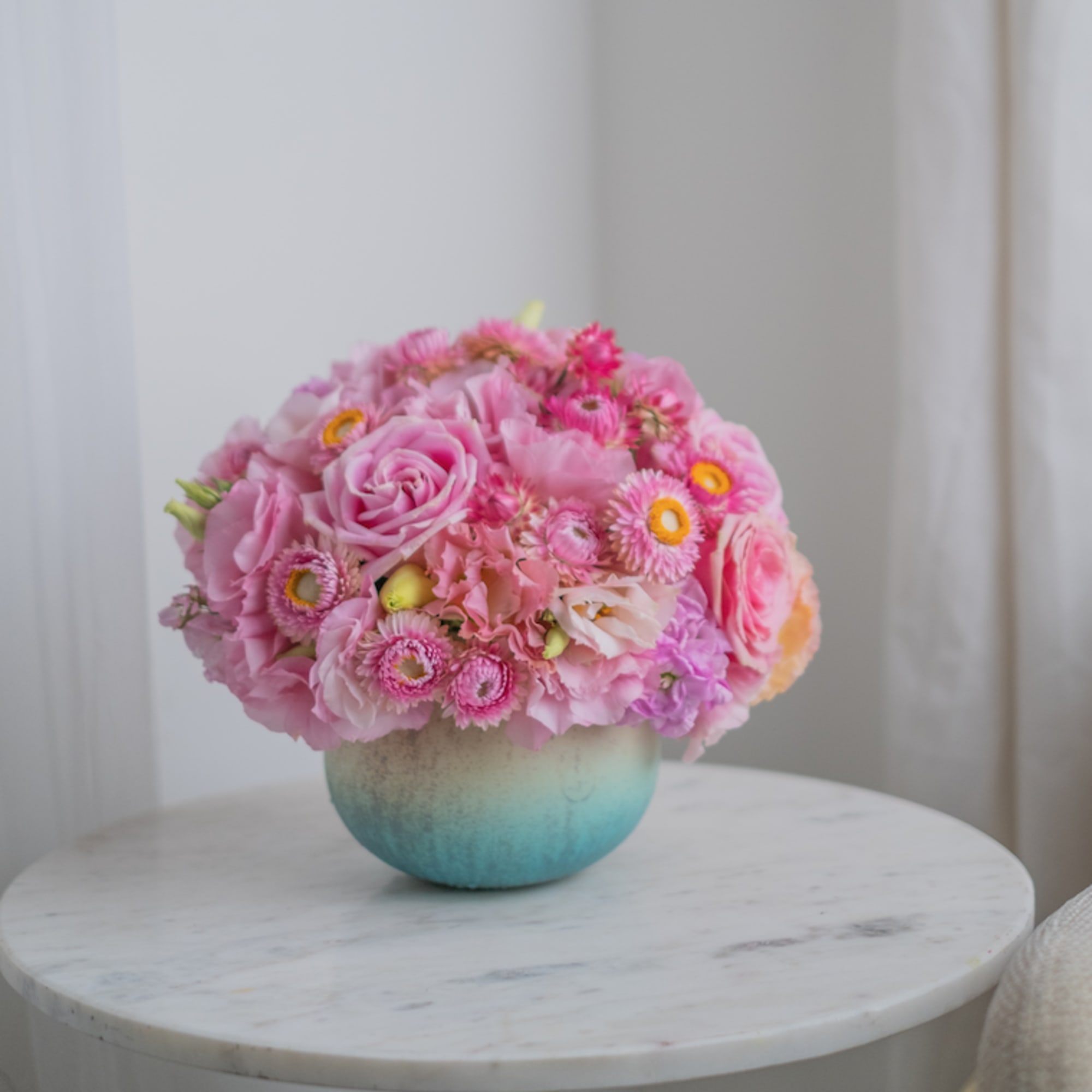 A delicate blue vase with bright pink shades of flowers. Like strawberry