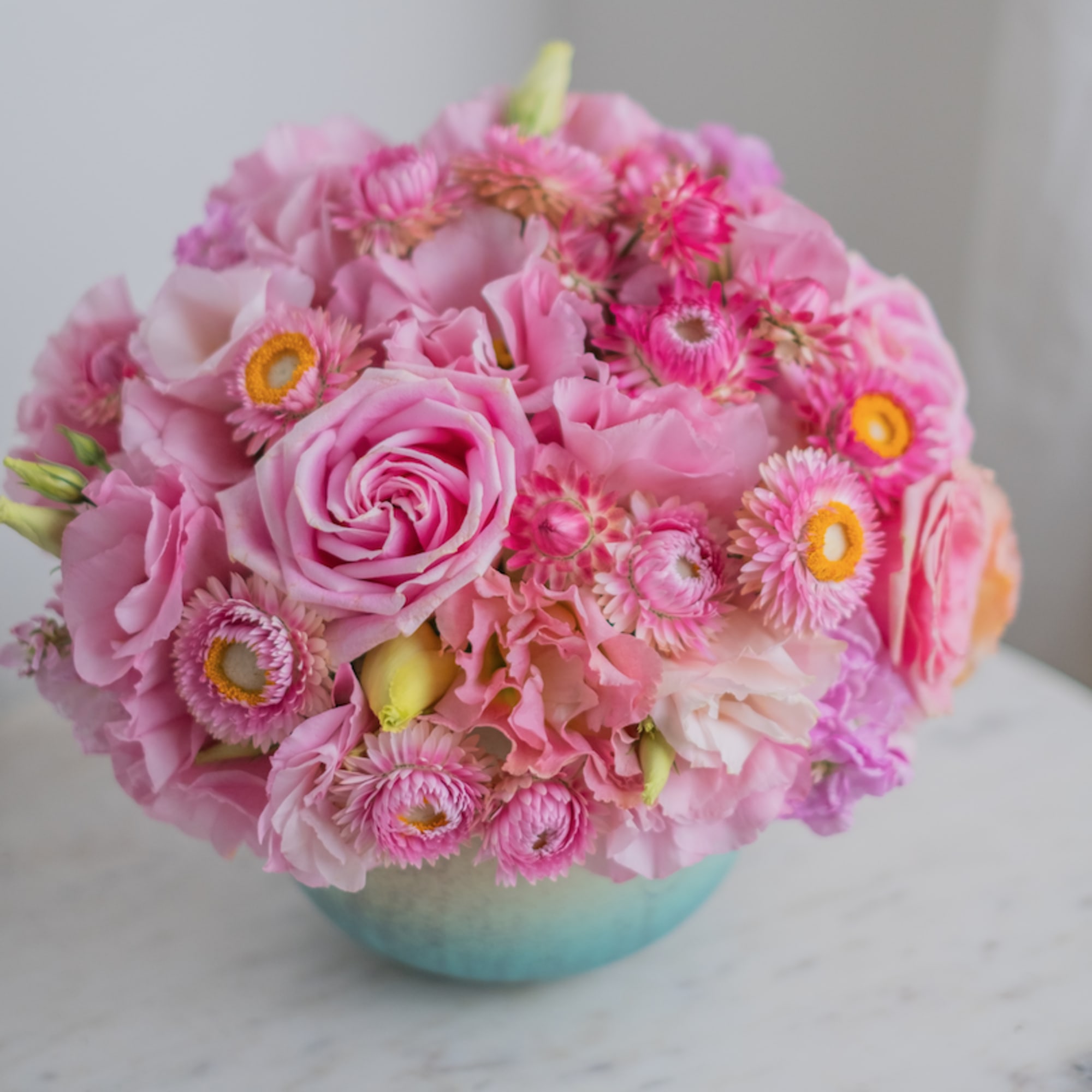 A delicate blue vase with bright pink shades of flowers. Like strawberry