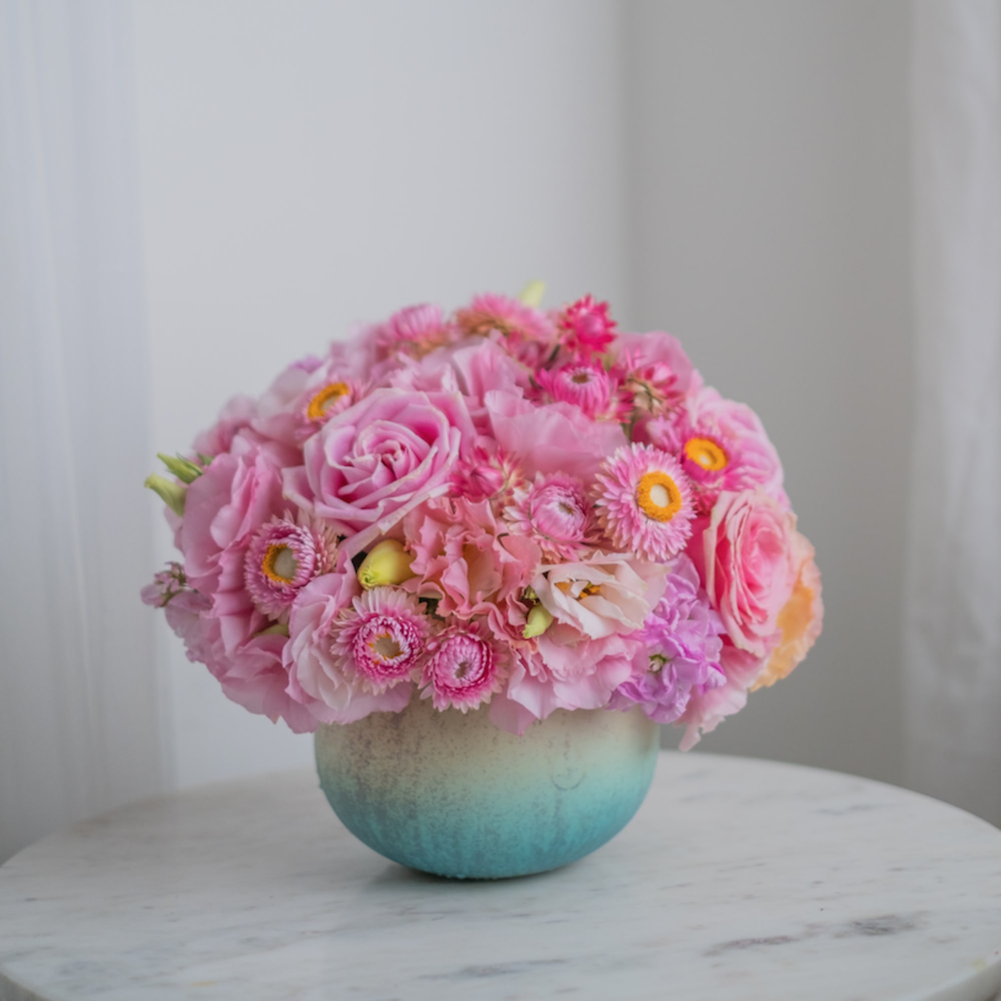 A delicate blue vase with bright pink shades of flowers. Like strawberry
