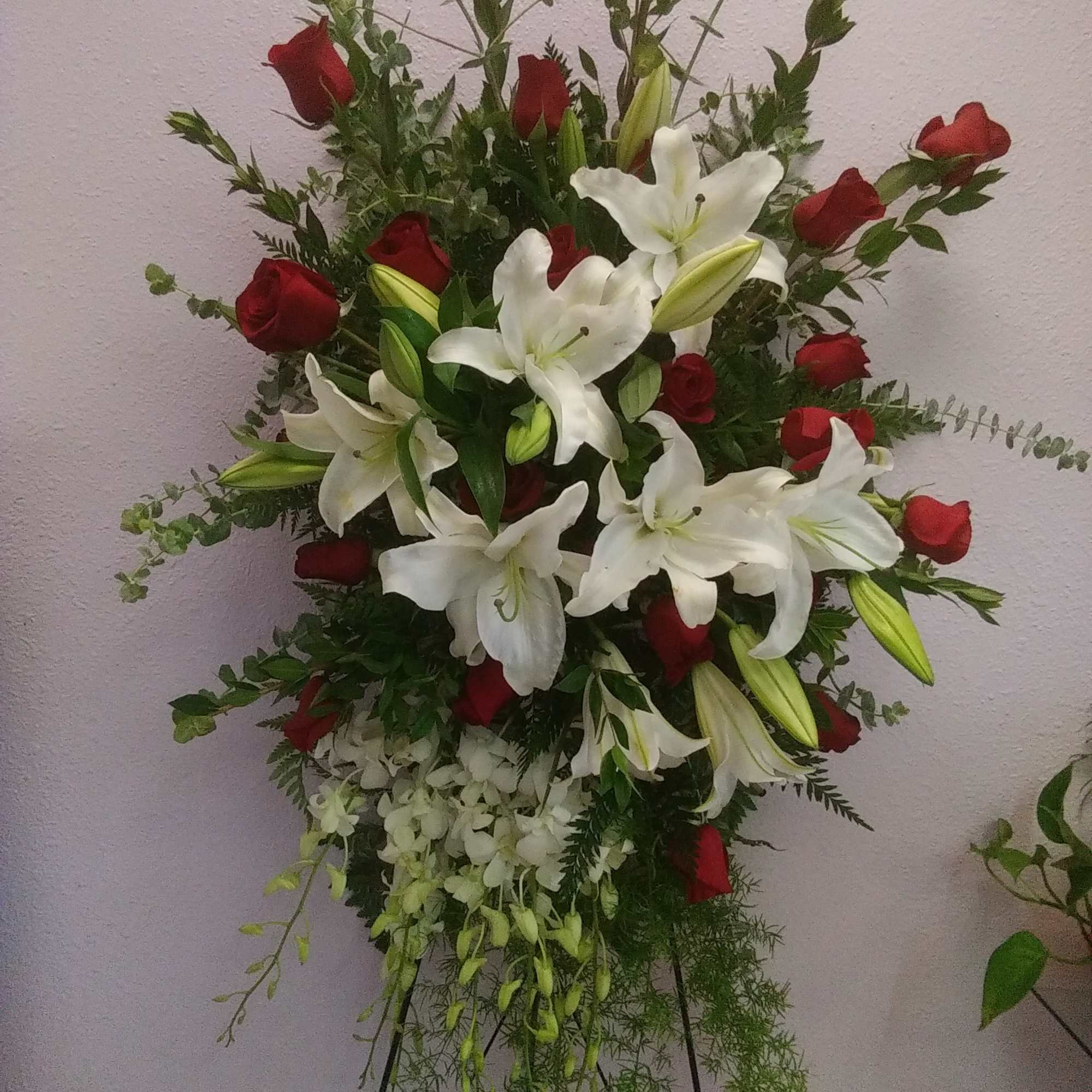 Contains Asiatic Lilies, red Roses, white Dendrobium Orchids, and other seasonal greens.