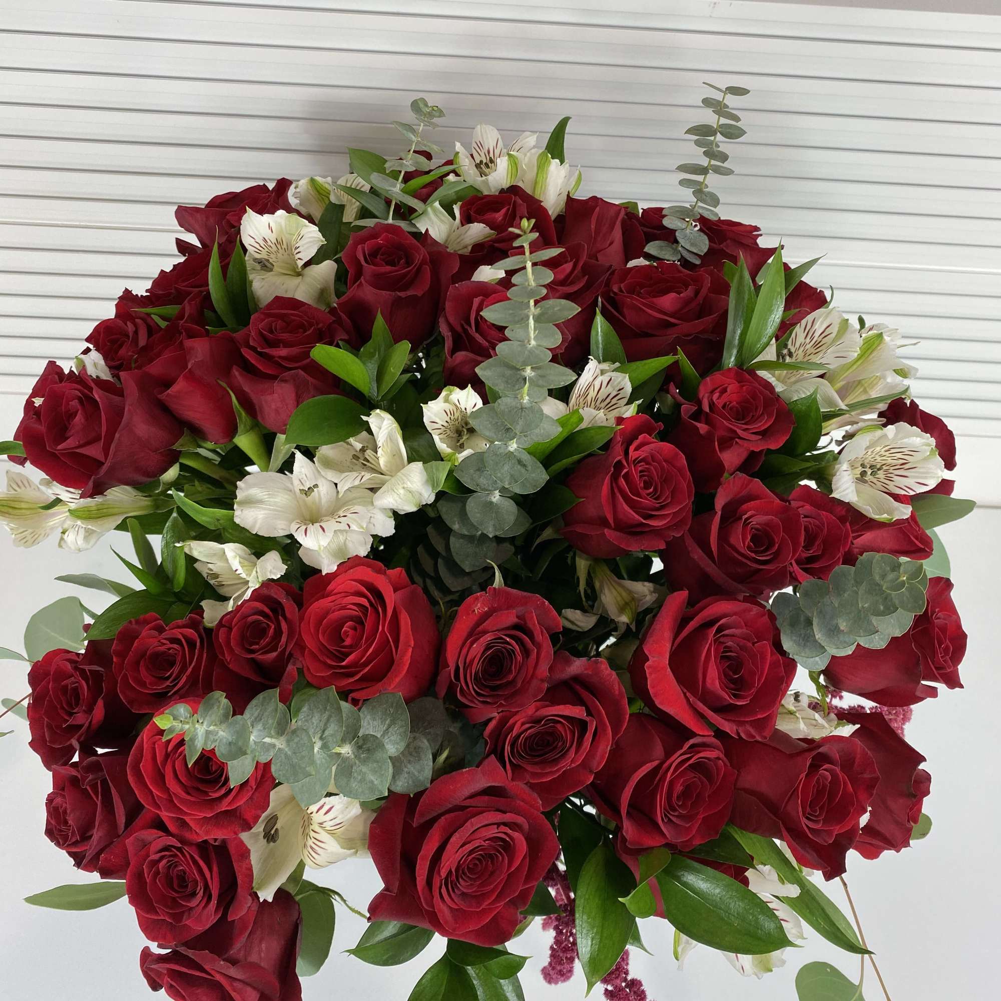 4 Dozen long stem red roses with white alstroemerias and rich greenery.