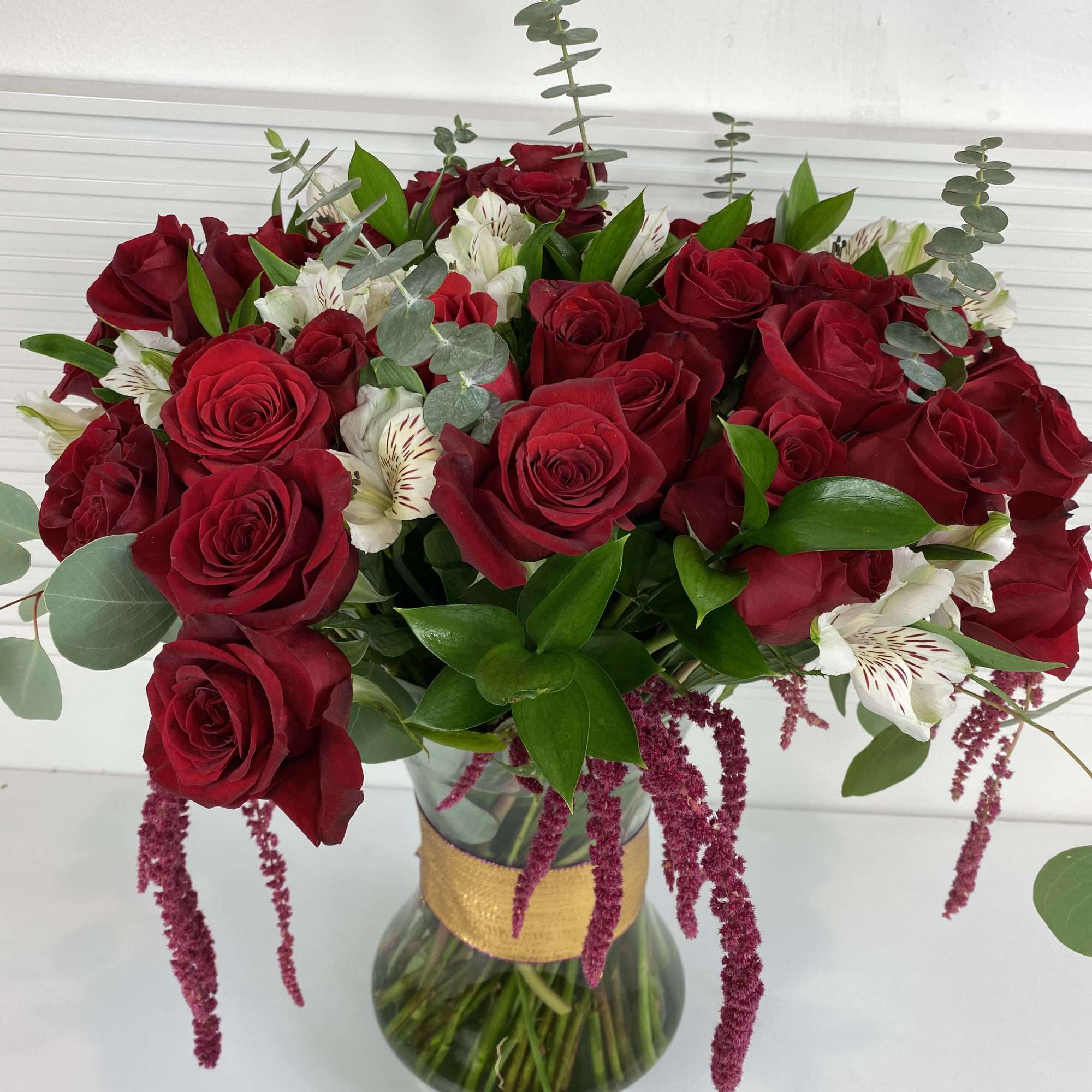 4 Dozen long stem red roses with white alstroemerias and rich greenery.