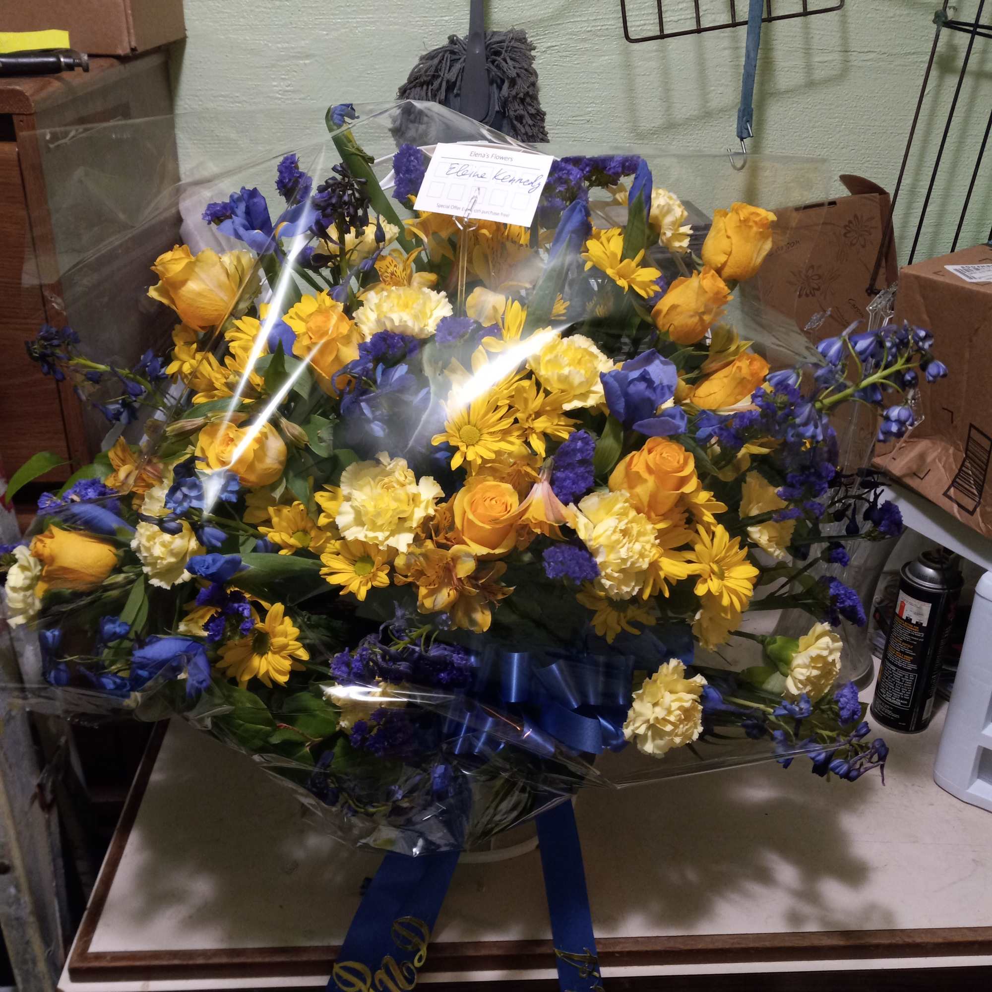 Bright yellow roses, carnations, daisies and alstroemeria mixed with blue irises, statice