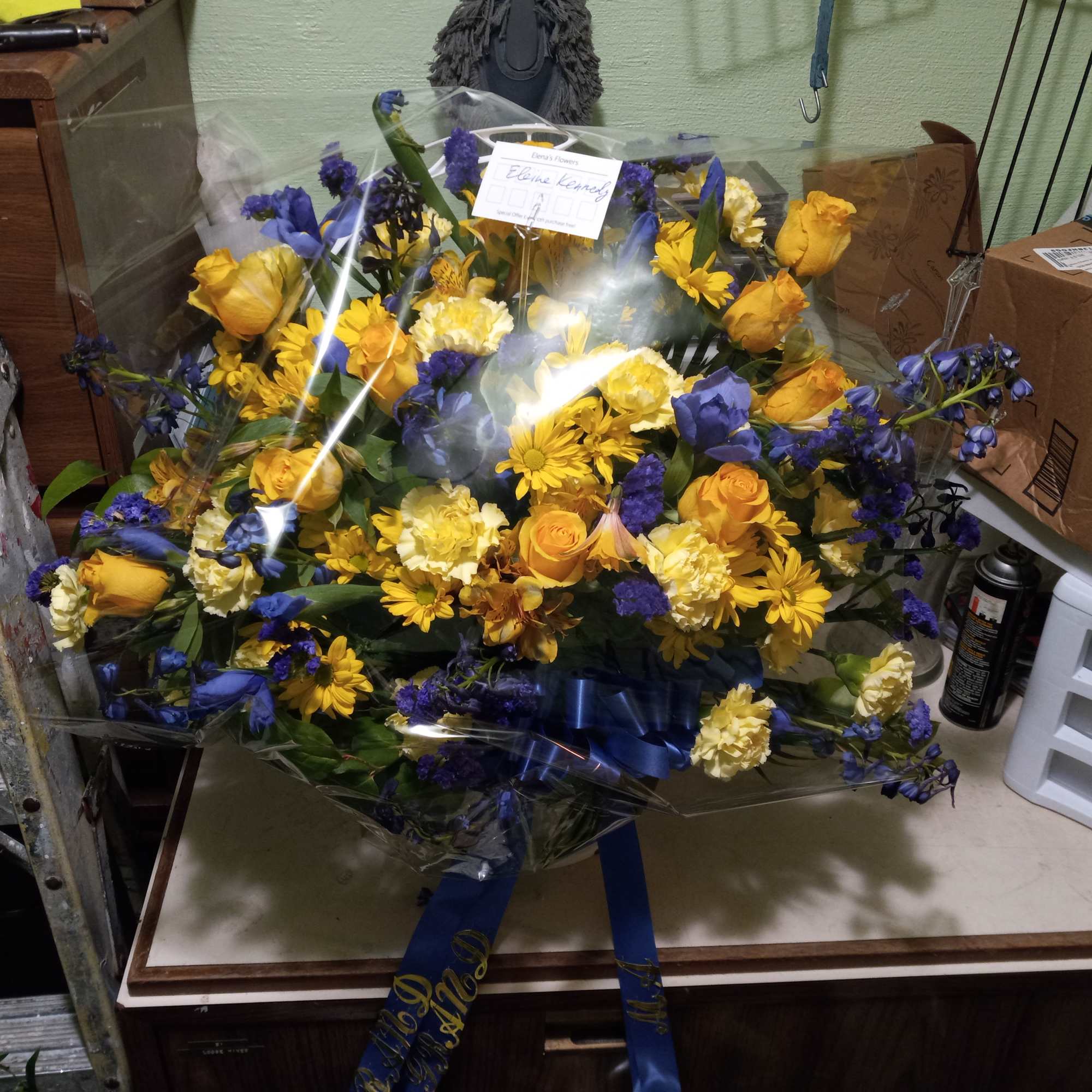 Bright yellow roses, carnations, daisies and alstroemeria mixed with blue irises, statice
