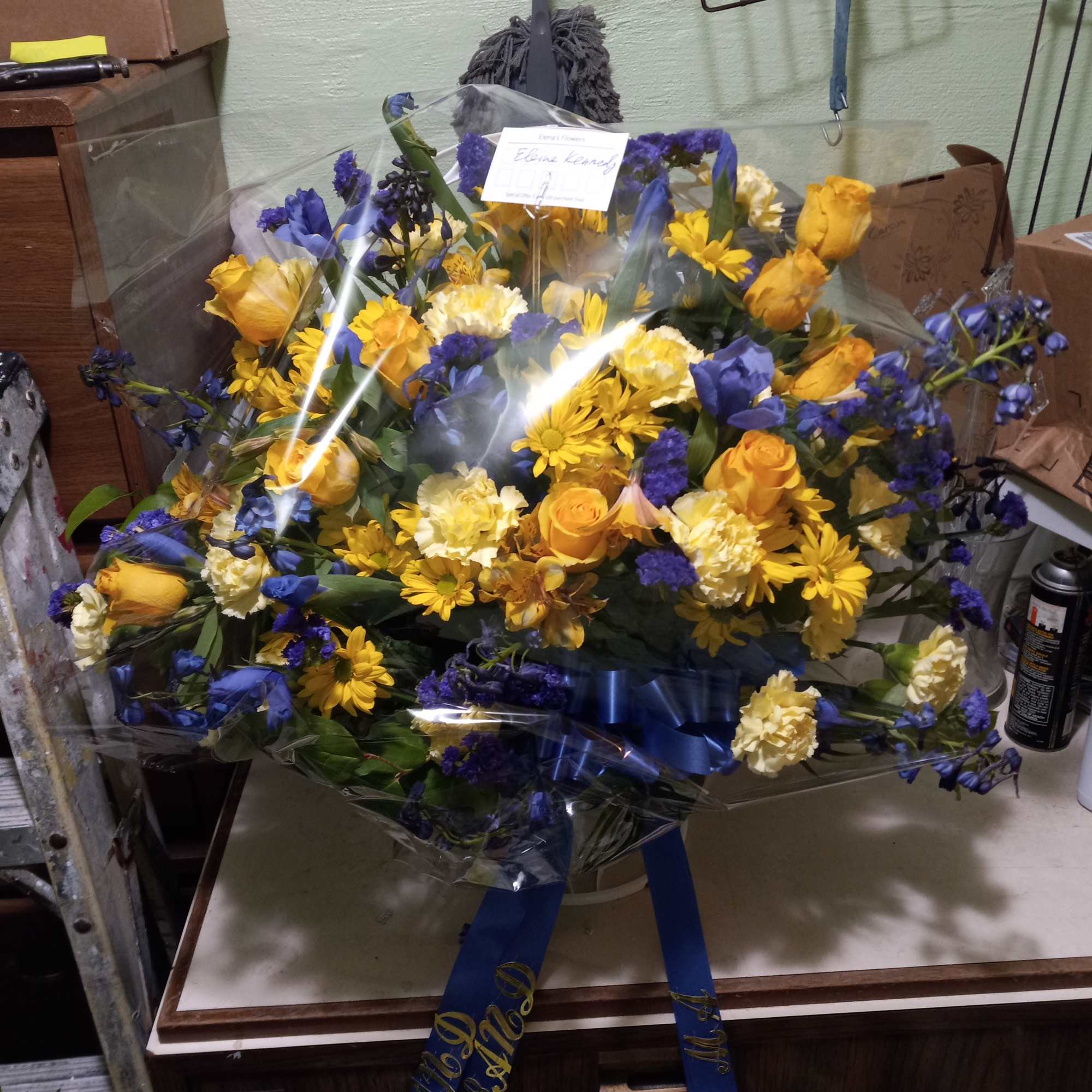 Bright yellow roses, carnations, daisies and alstroemeria mixed with blue irises, statice
