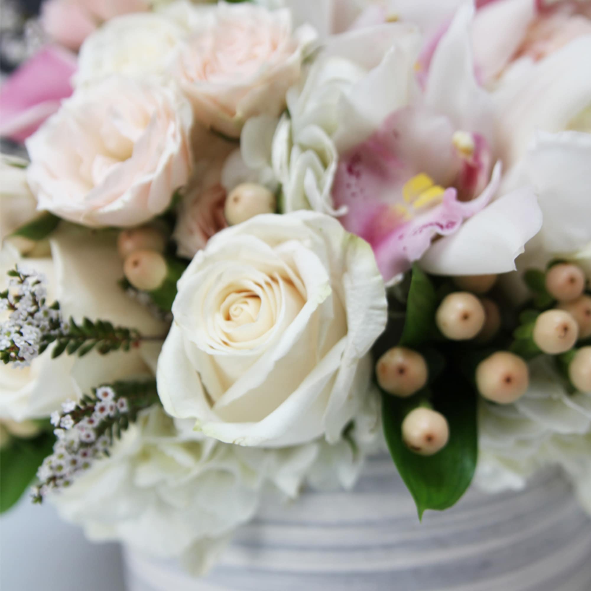 Beautiful ceramic vase filled with Cymbidium orchids, roses and hydrangeas