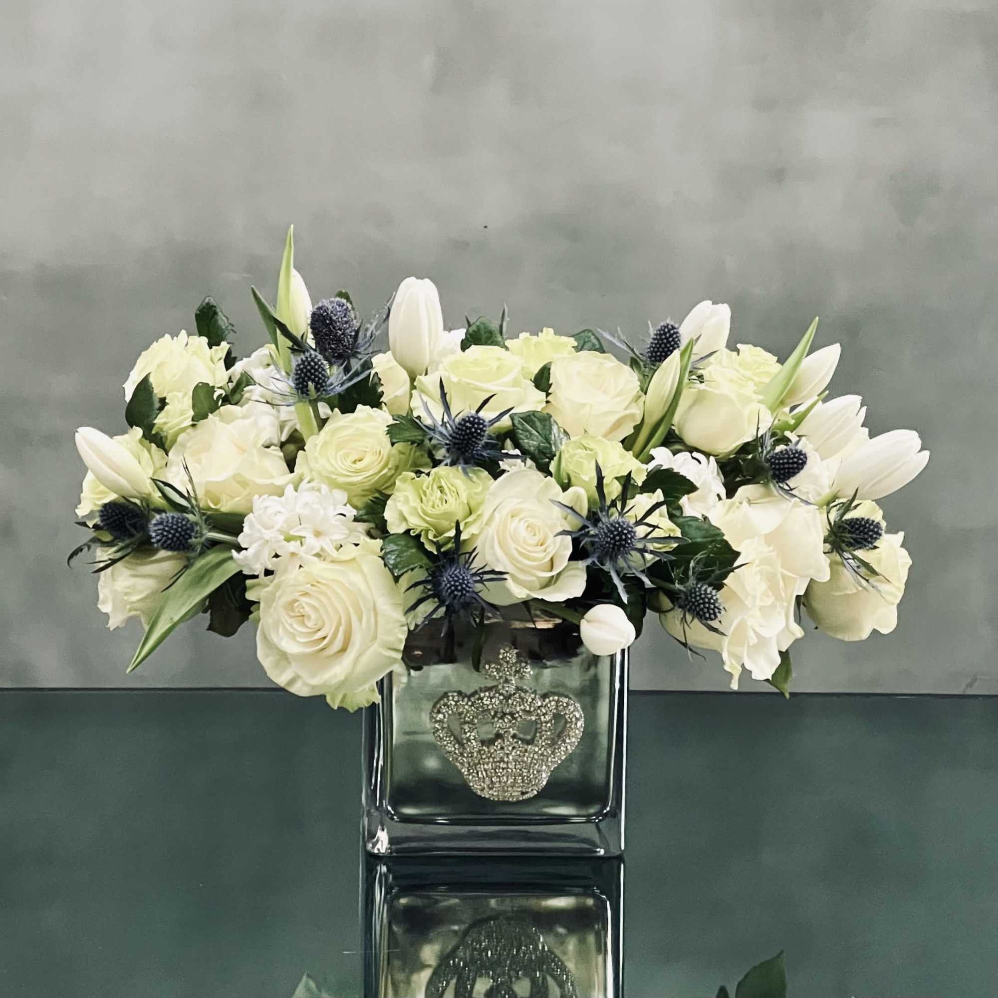 A cluster of white tulips, roses, hyacinths and thistle in a bejeweled