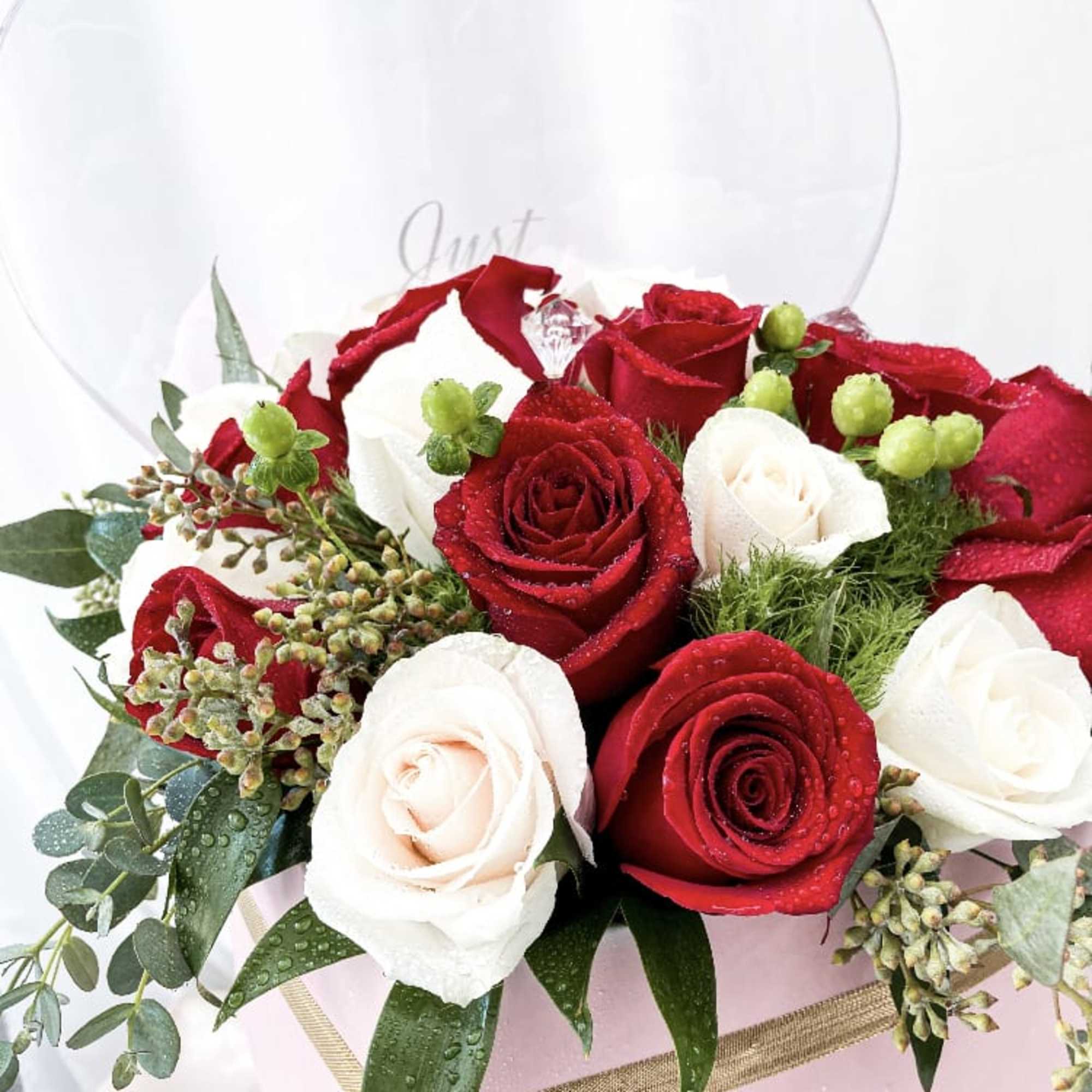 This special arrangement consists of roses and a variety of greens all
