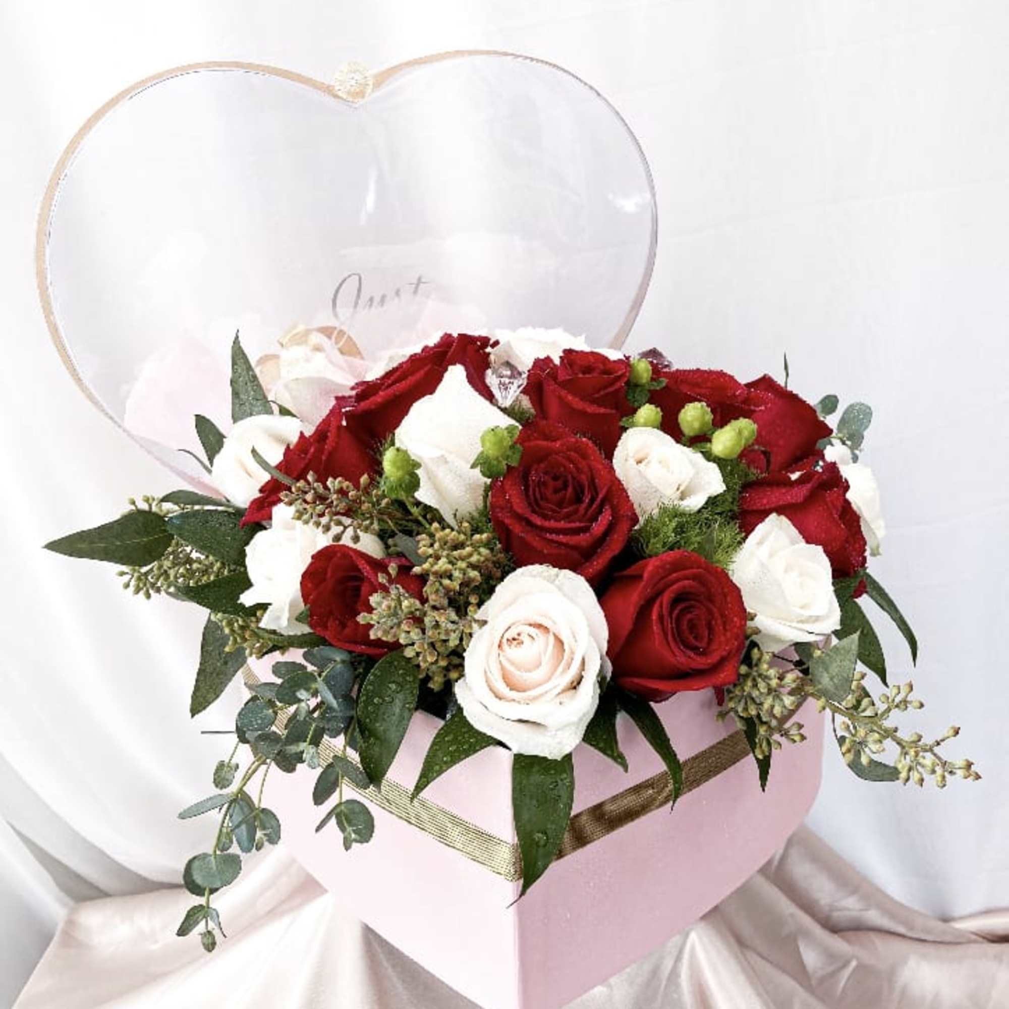 This special arrangement consists of roses and a variety of greens all