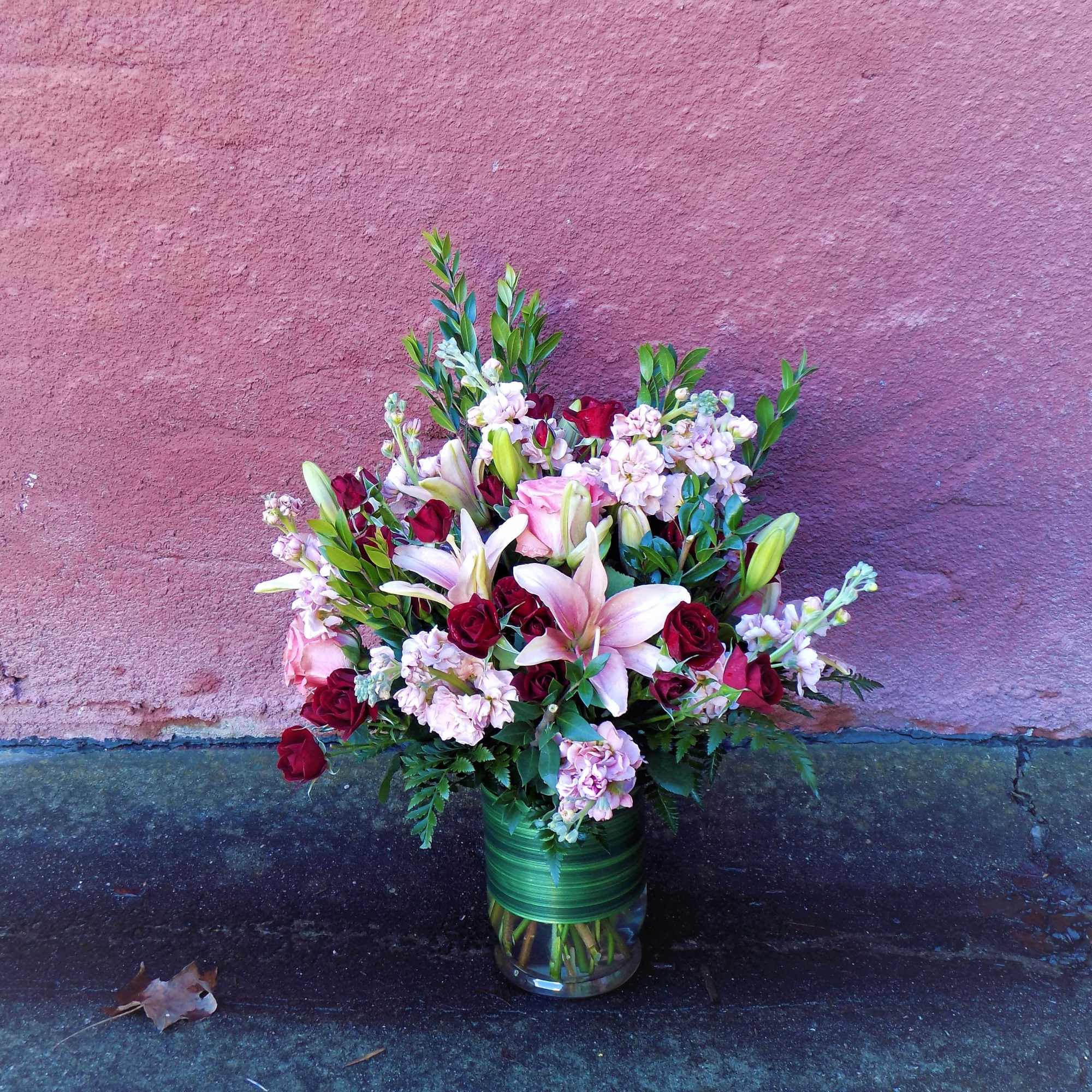 A stunning array of pink roses, red spray roses, Asiatic lilies, and