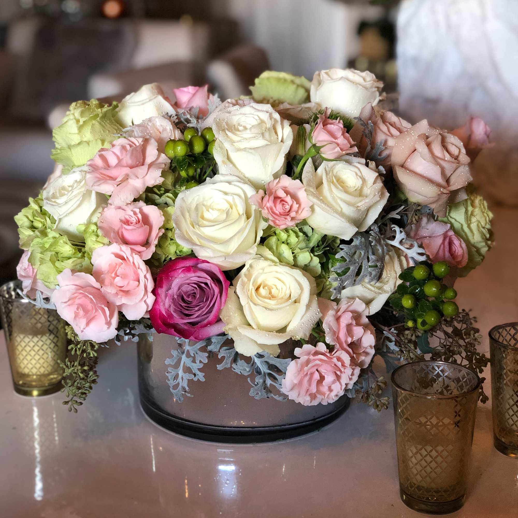 A low and lush arrangement overflowing with roses, hydrangeas, and various elegant