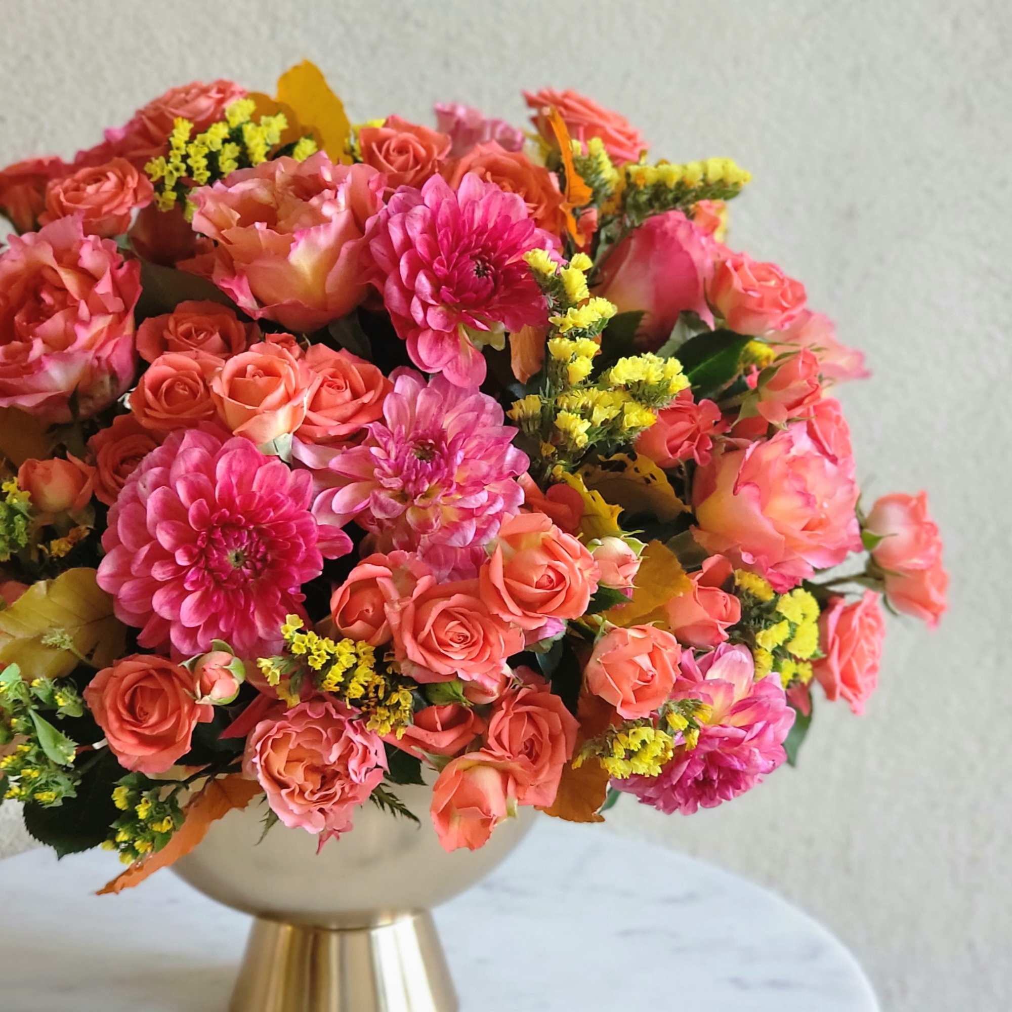 Bouquets and compositions of a bright flowers in a golden vase will