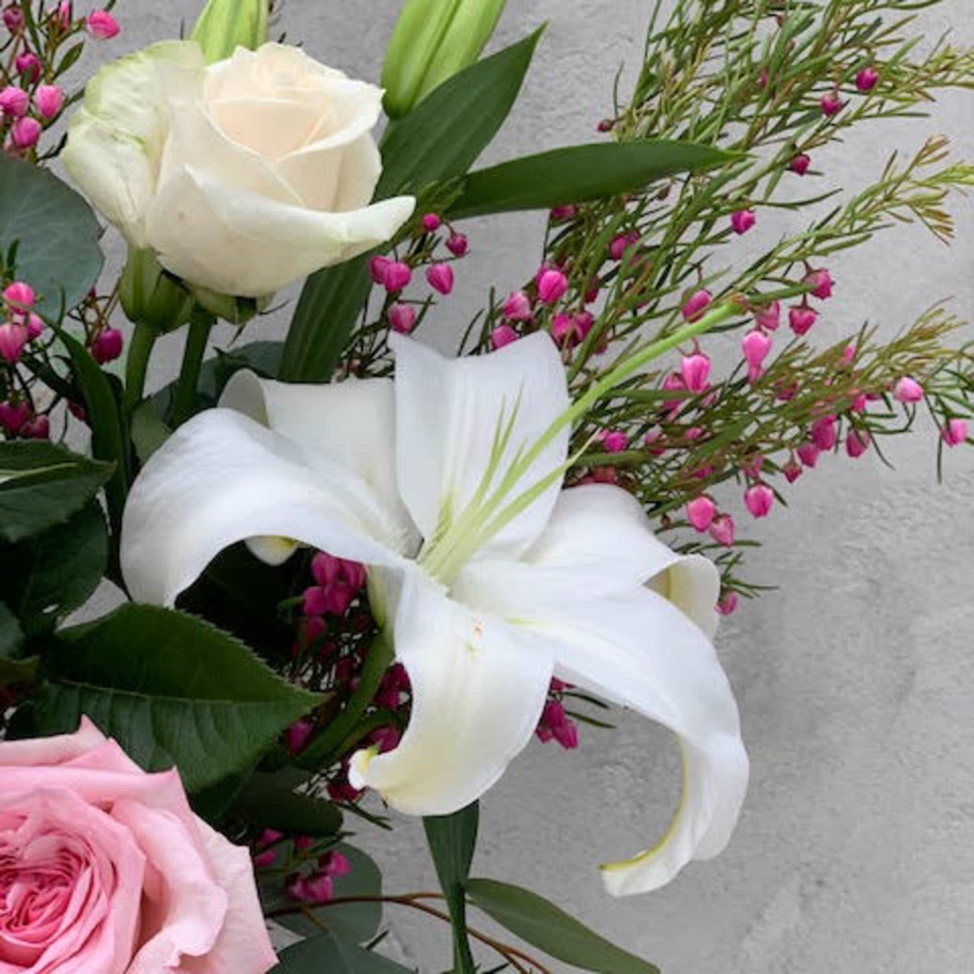 A beautiful bouquet of pink and white roses with white lilies in