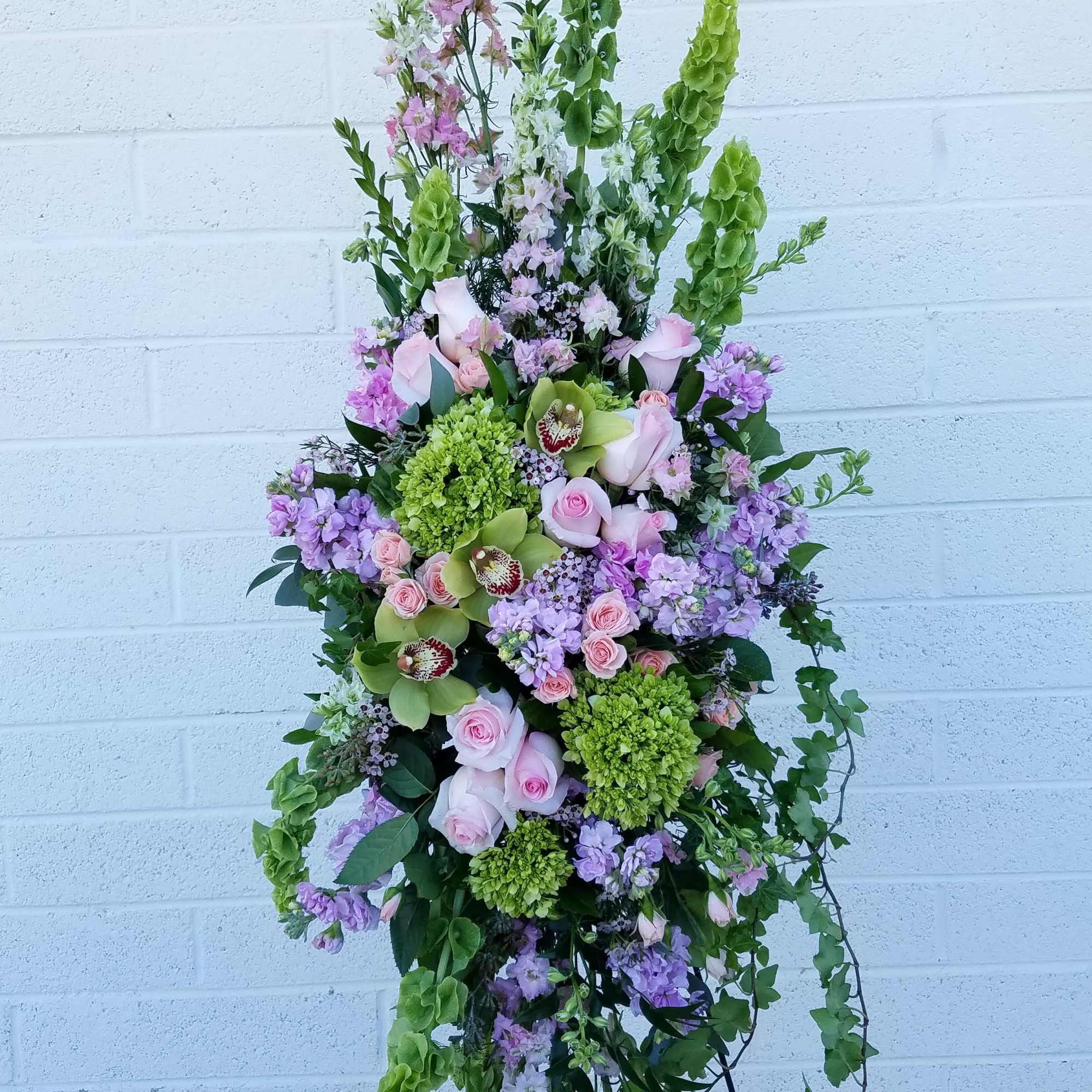 A beautiful easel spray in peaceful pastel tones featuring green hydrangea, larkspur A beautiful easel spray in peaceful pastel tones featuring green hydrangea, larkspur