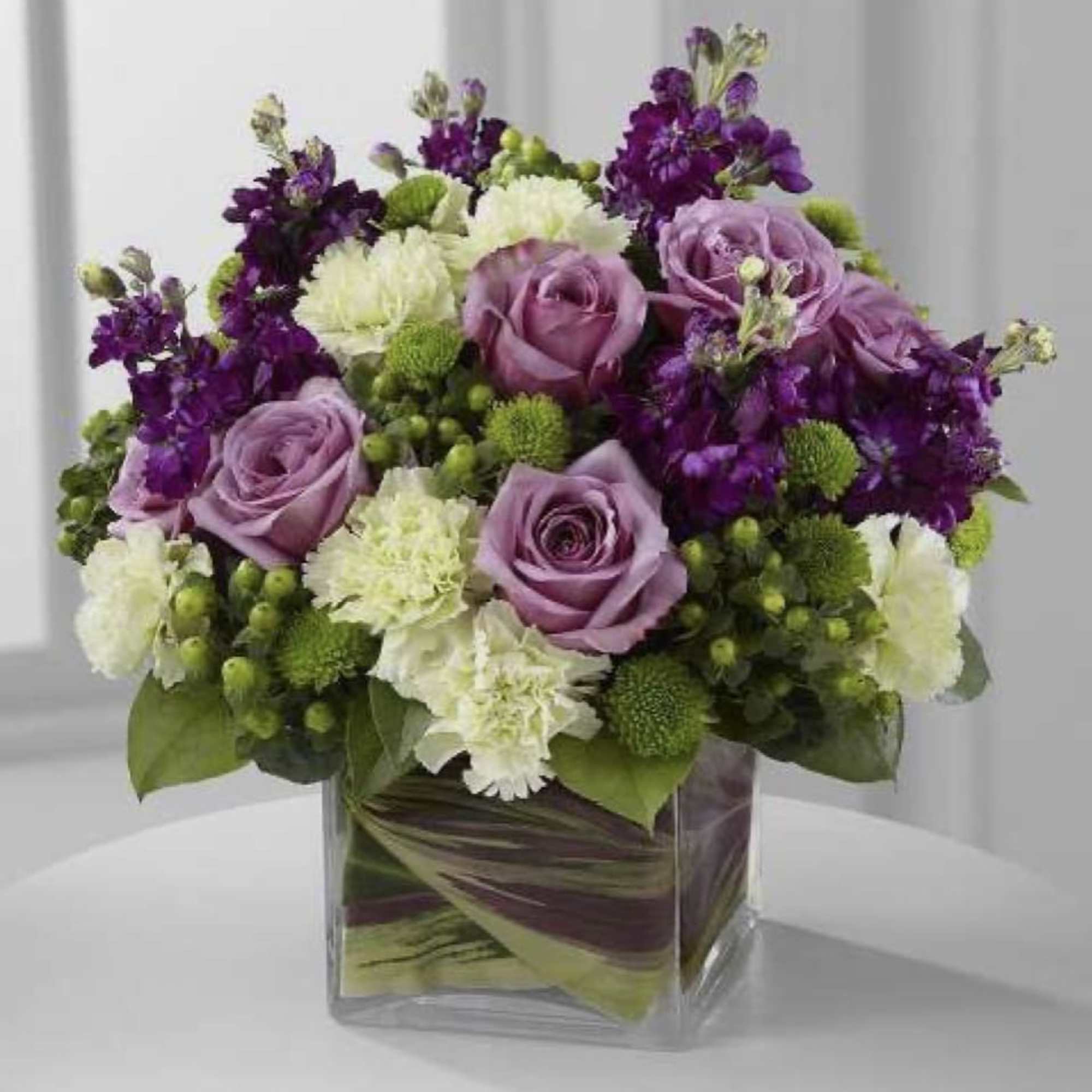 A lavender color centerpiece with roses and other beautiful seasonal flowers 