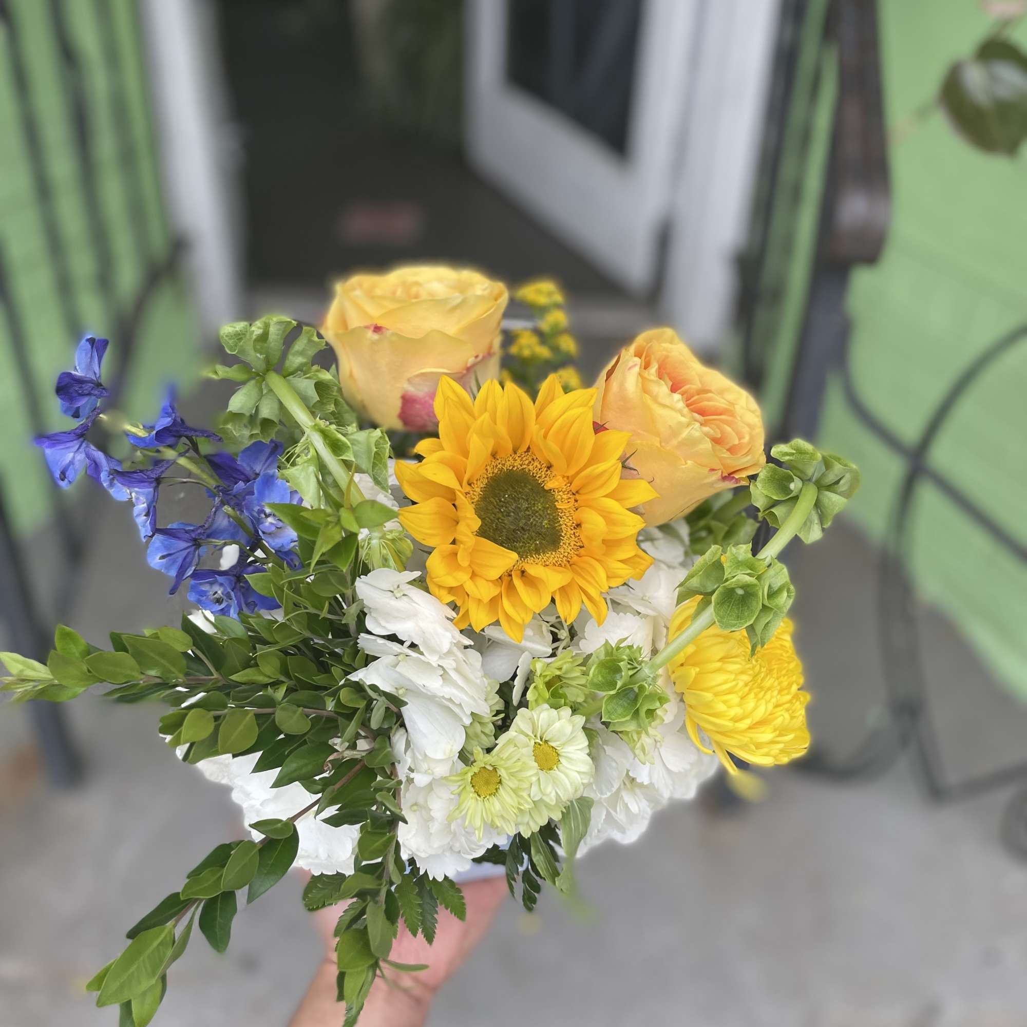 This beautiful arrangement has, yellow sunflowers, yellow roses, white hydrangea, green bells