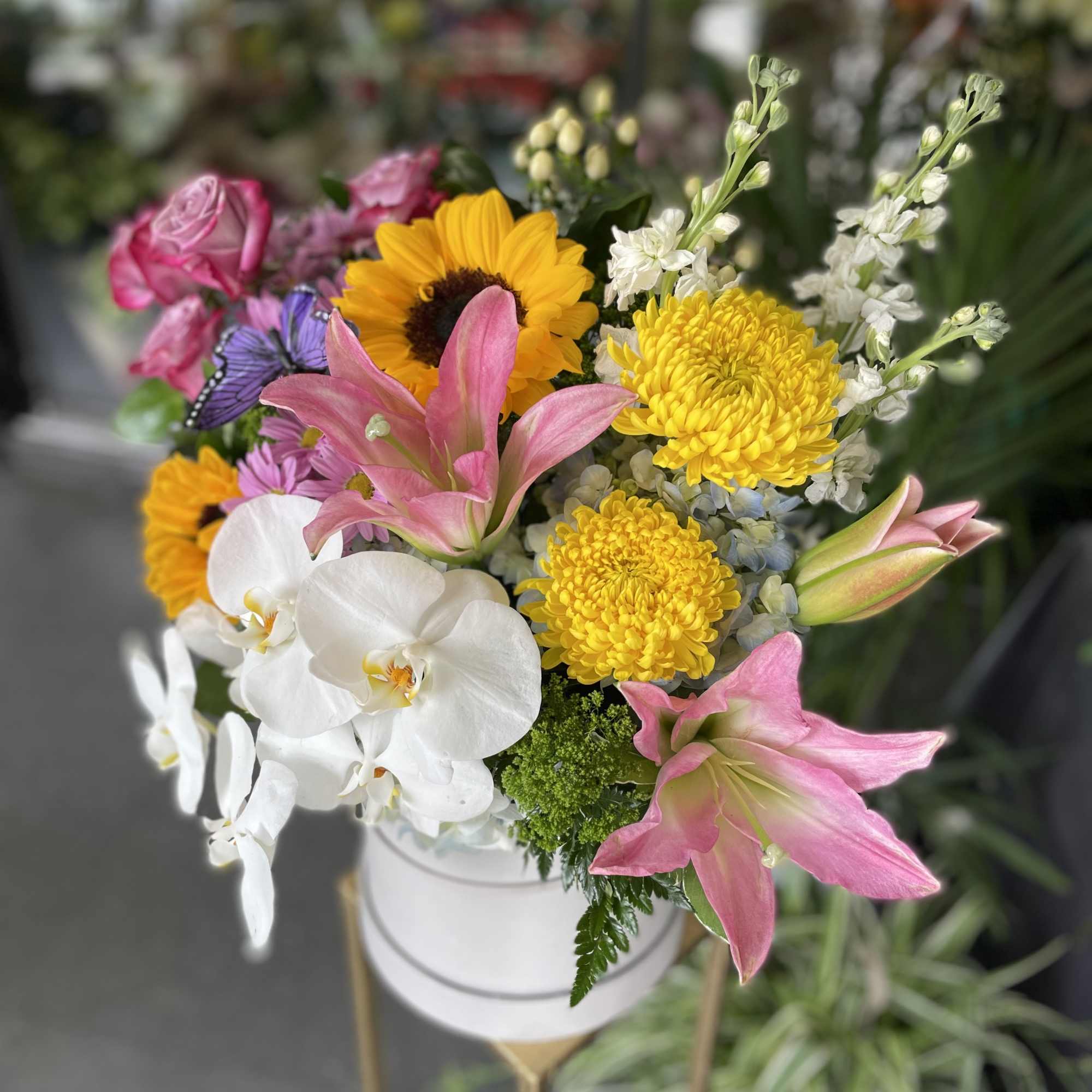This beautiful arrangement has white orchid, pink lily&rsquo;s, lavender roses, sunflower, white