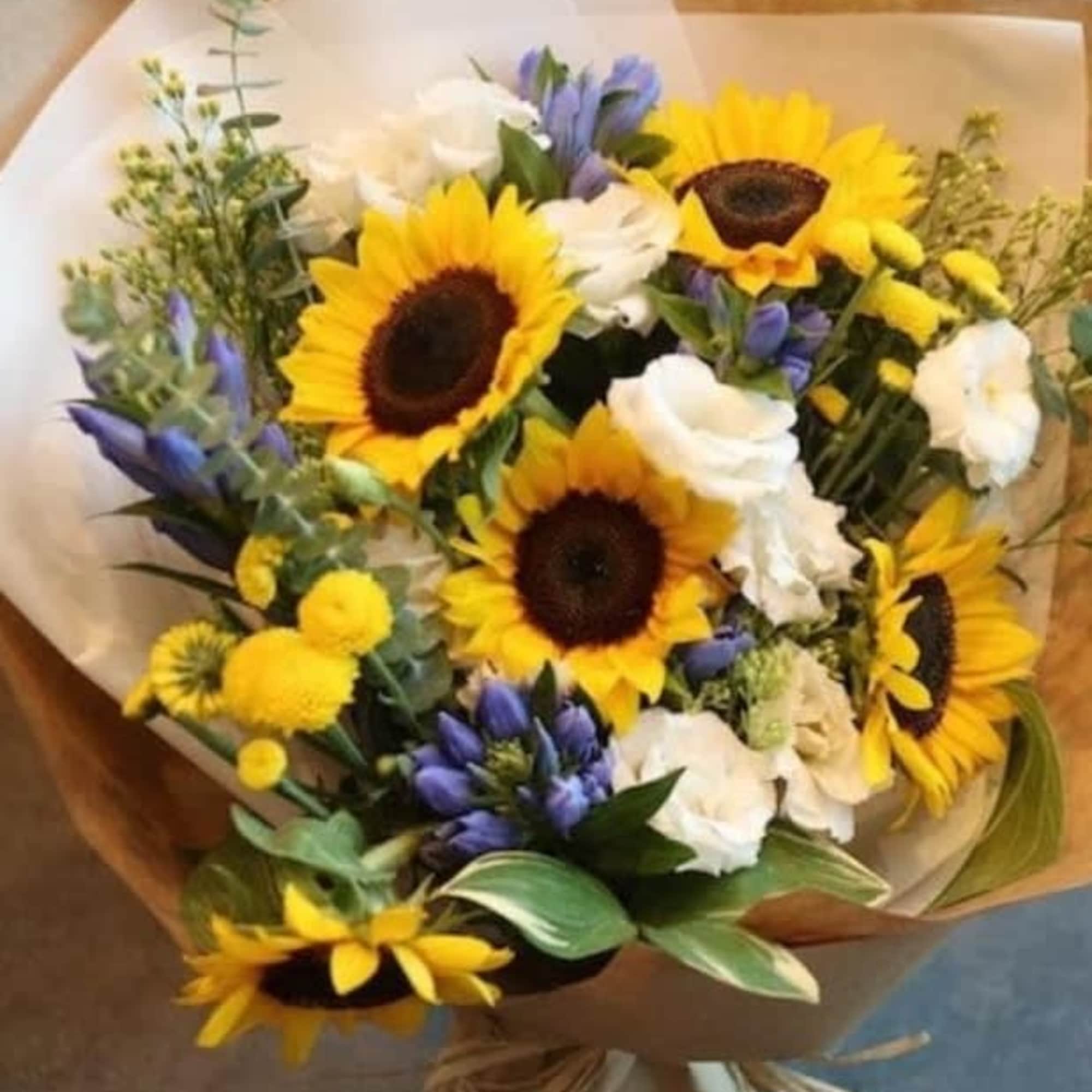 Mixture of sunflowers and compliment filler flowers in the brown paper wrapped