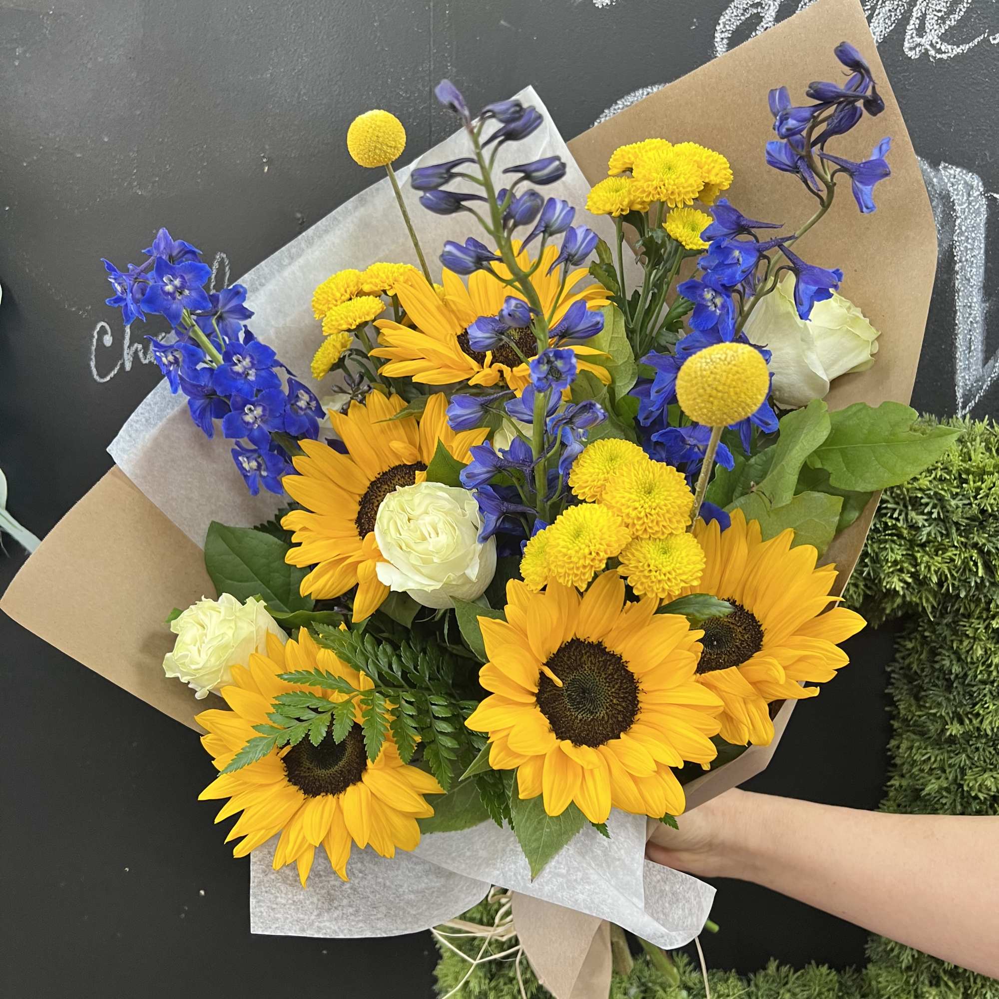 Mixture of sunflowers and compliment filler flowers in the brown paper wrapped