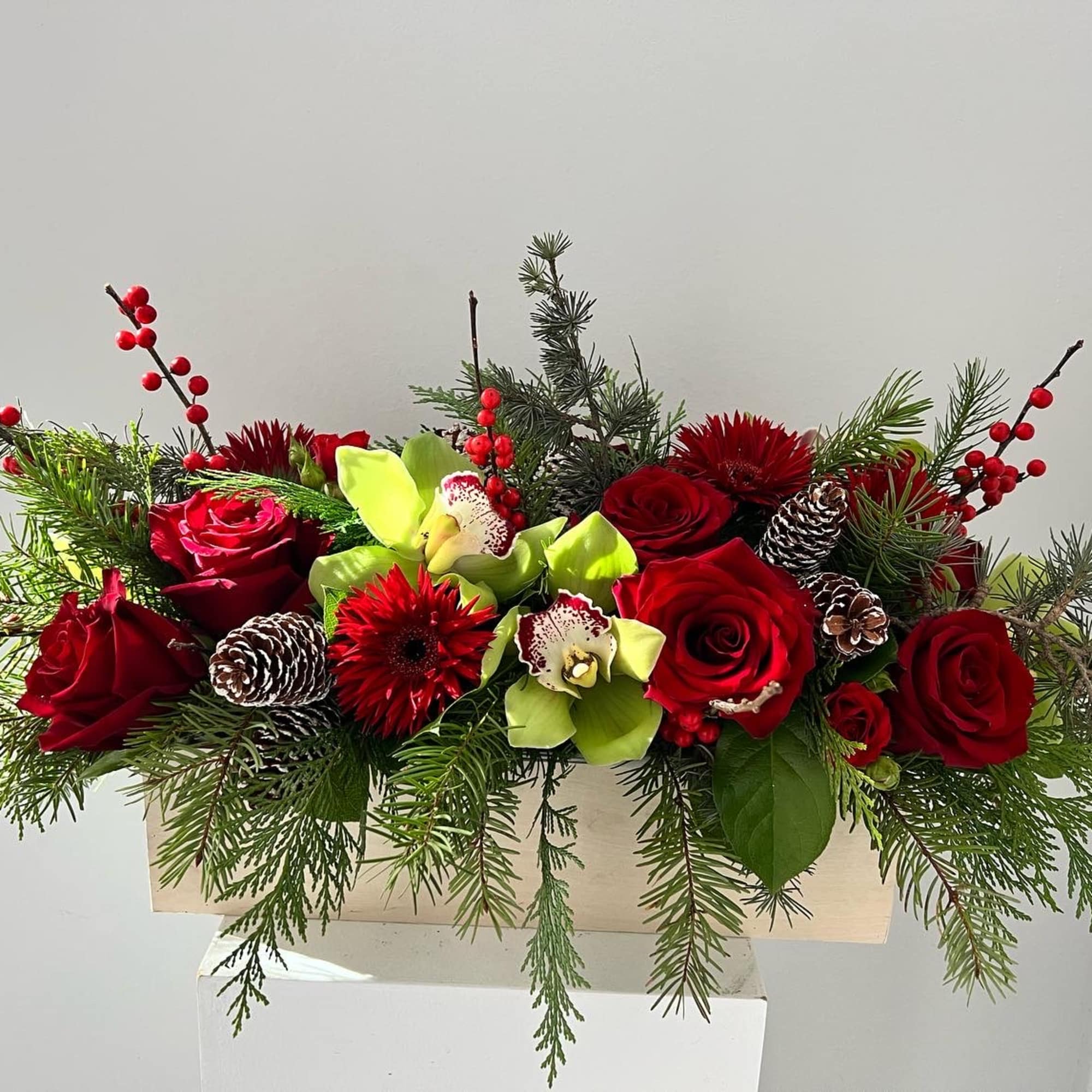 Christmas centerpiece in a box with roses, orchids, gerbera daisies, berries and
