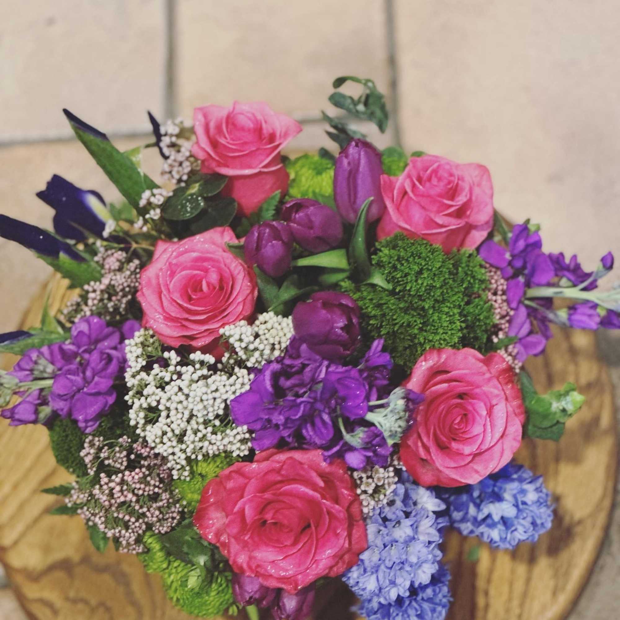 This arrangement includes green dianthus, blue iris, white tulips, hyacinths, and other