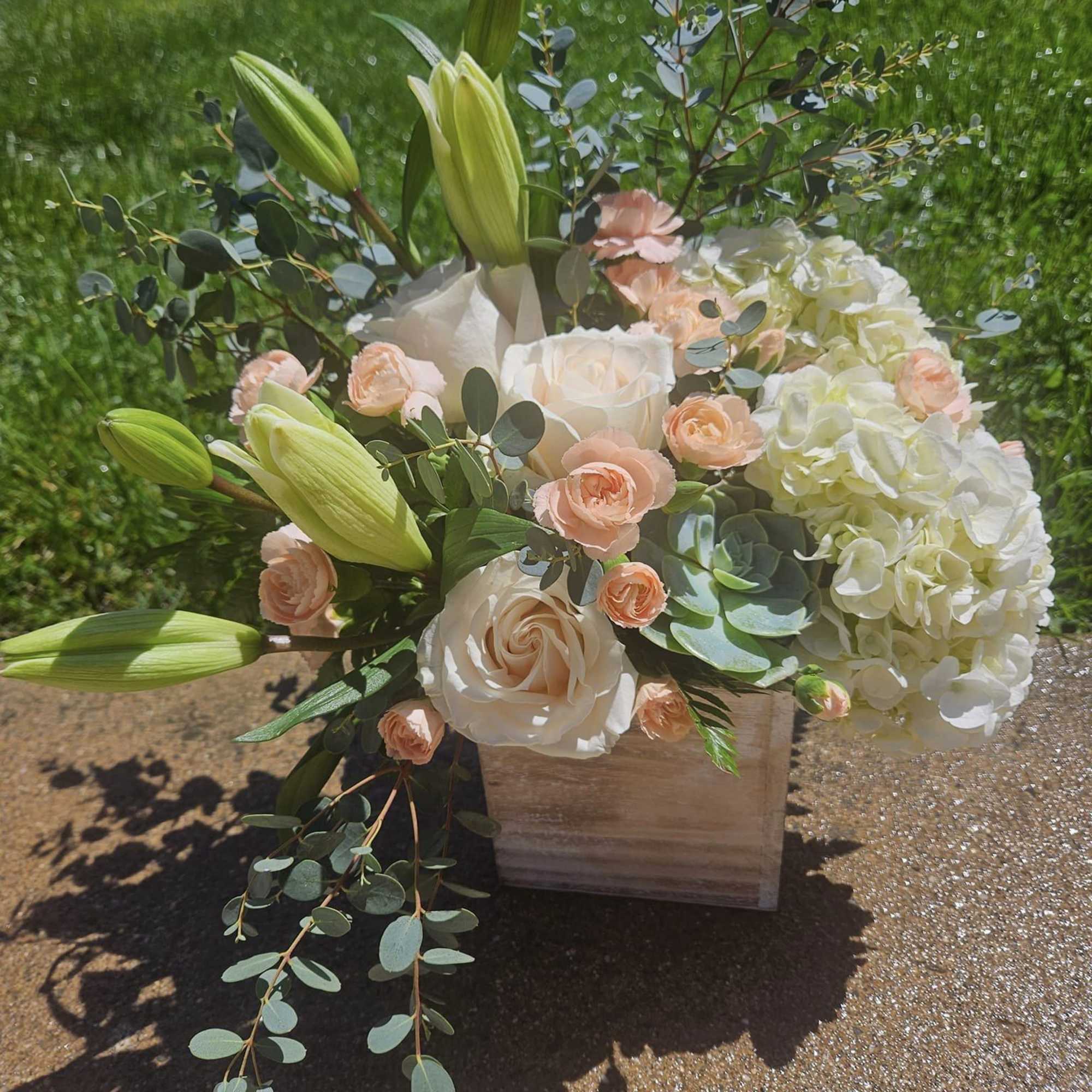 White and peach fresh flowers surrounding a succulent.
