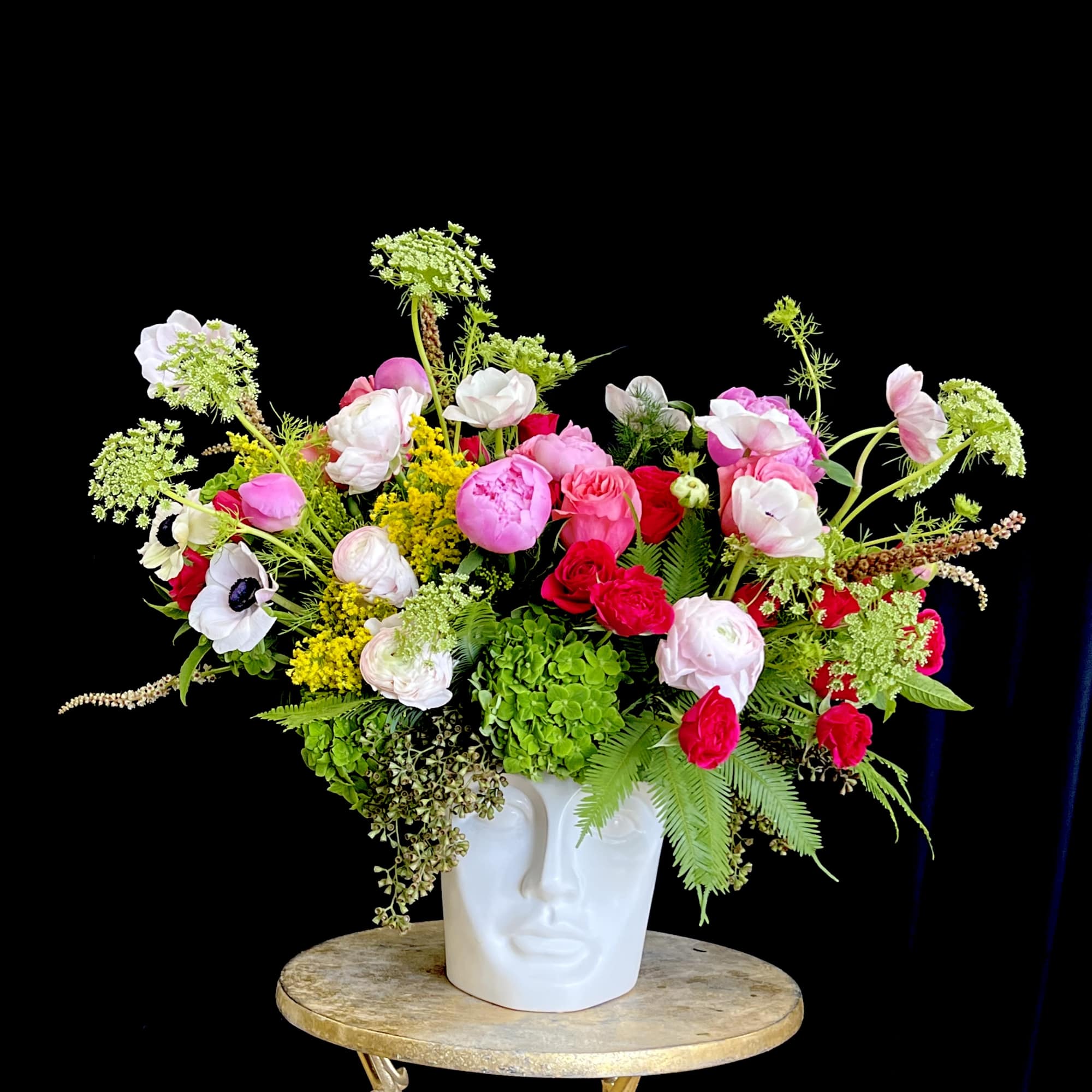 A modern arrangement of vibrant orchids and sculptural greens.