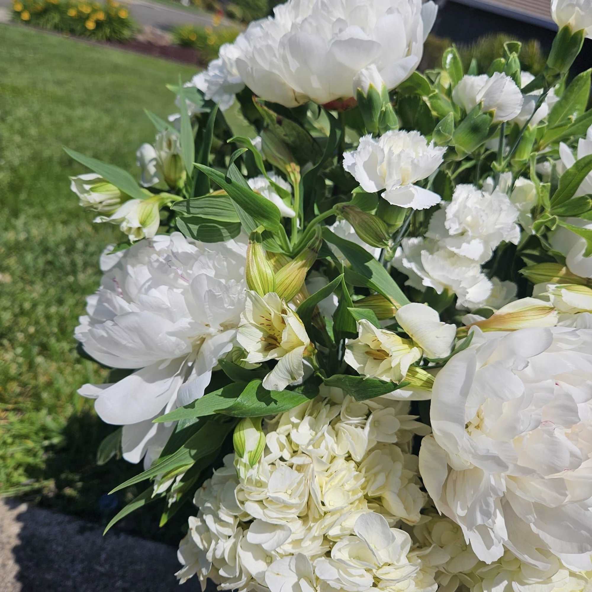 All the freshest white flowers in season in a vase with greens