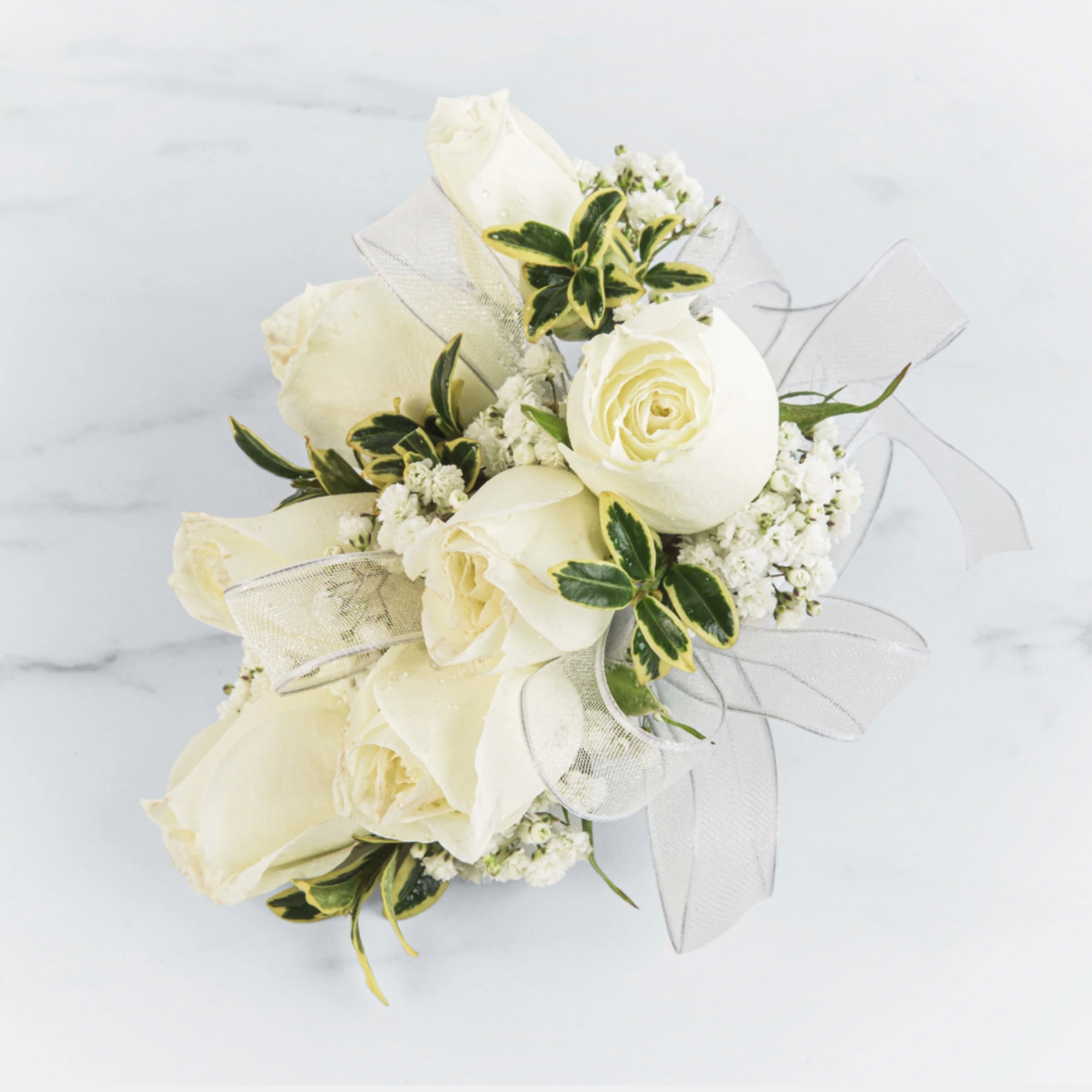 A classic white corsage with silver sheer ribbon, this wrist arrangement looks