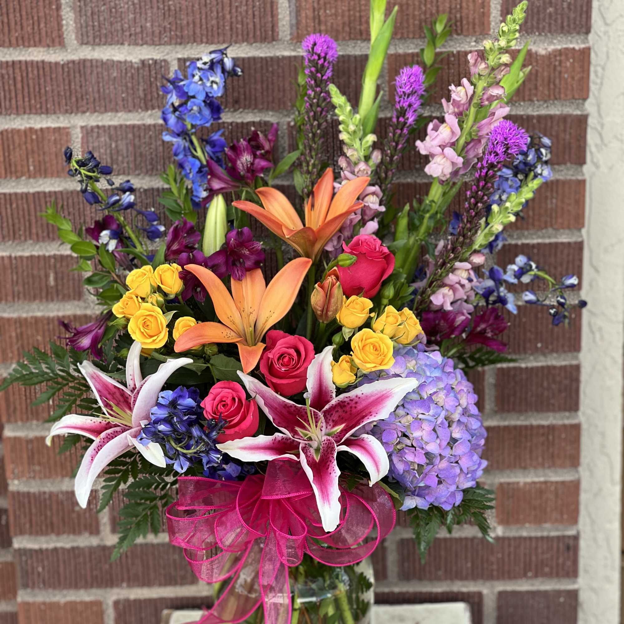 This colorful bouquet includes purple hydrangea, pink roses, yellow spray roses, orange This colorful bouquet includes purple hydrangea, pink roses, yellow spray roses, orange
