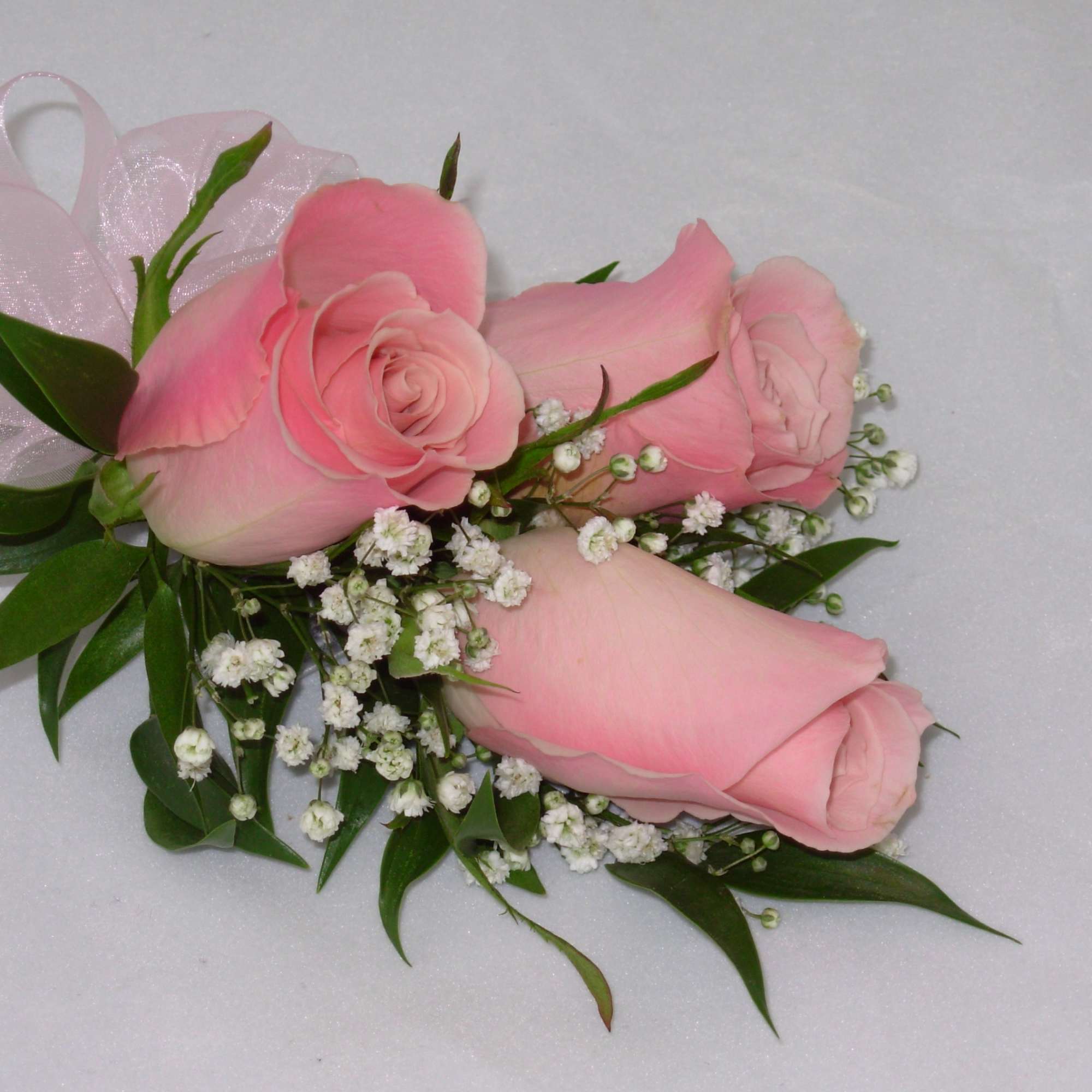 This beautiful corsage features three light pink roses along with a light This beautiful corsage features three light pink roses along with a light