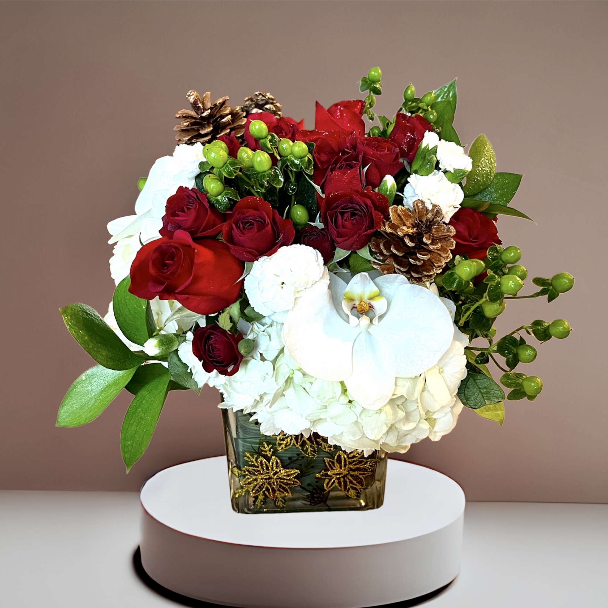 A festive holiday mix of roses, hydrangea, berries and pinecones in a
