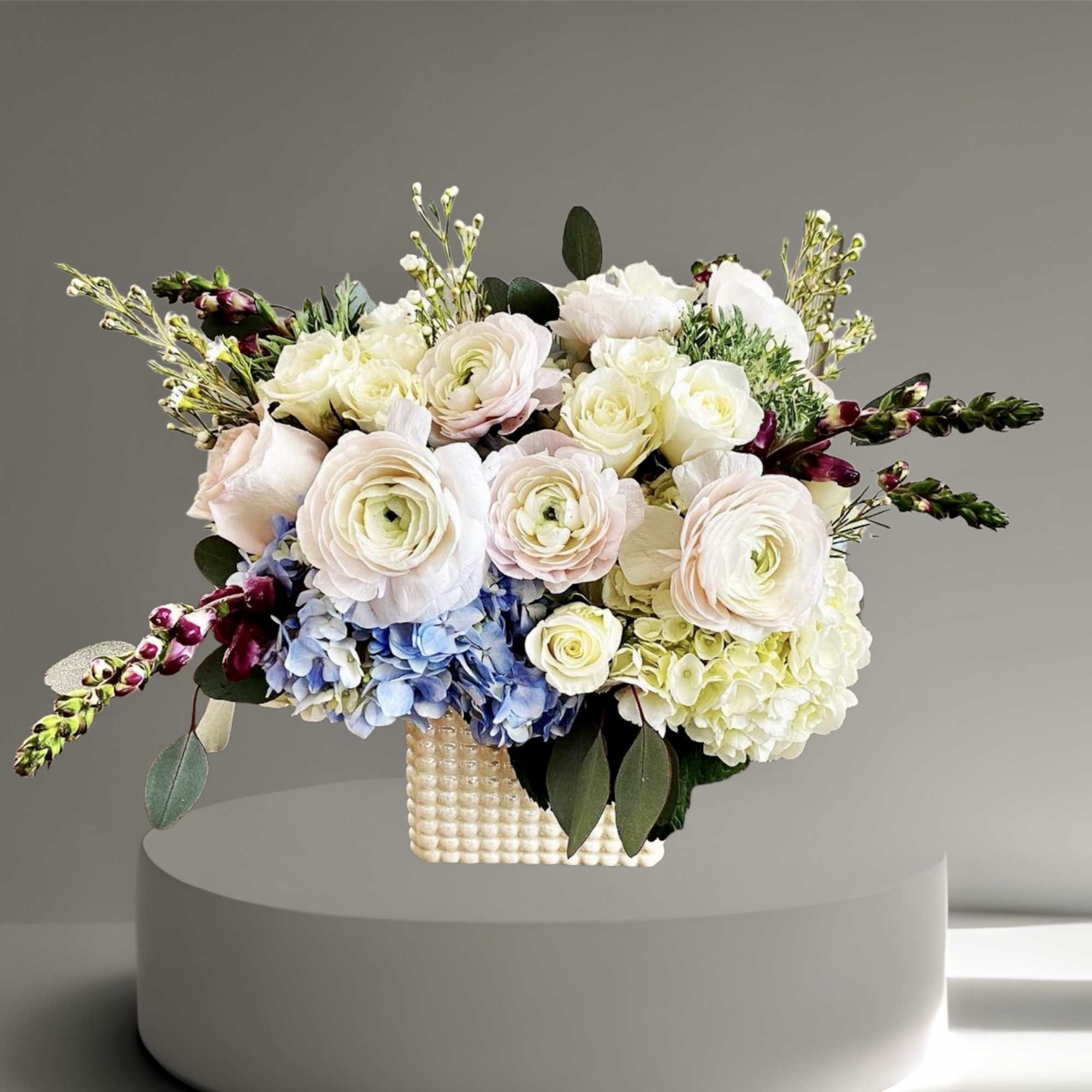 A sweet mix of hydrangea, ranunculus, snap dragon, wax flower, and foliage