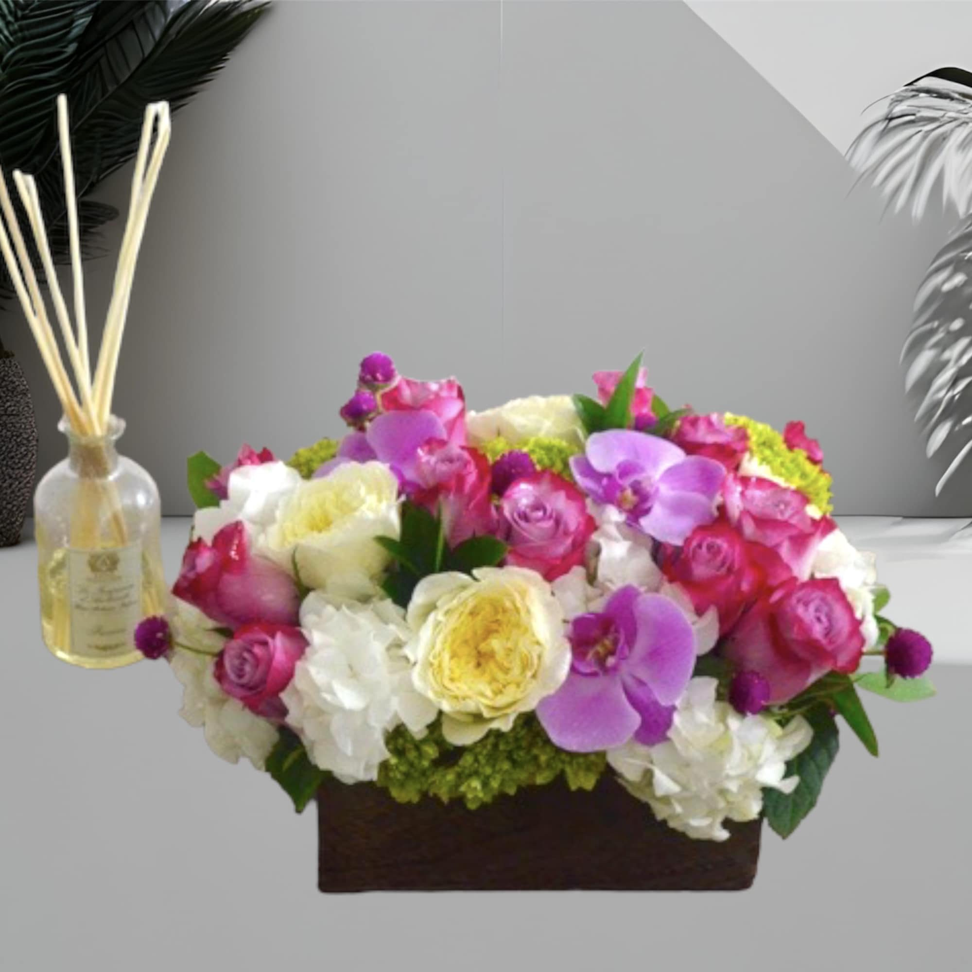 A lovely mix of roses, hydrangea, orchids, and foliage in a wooden