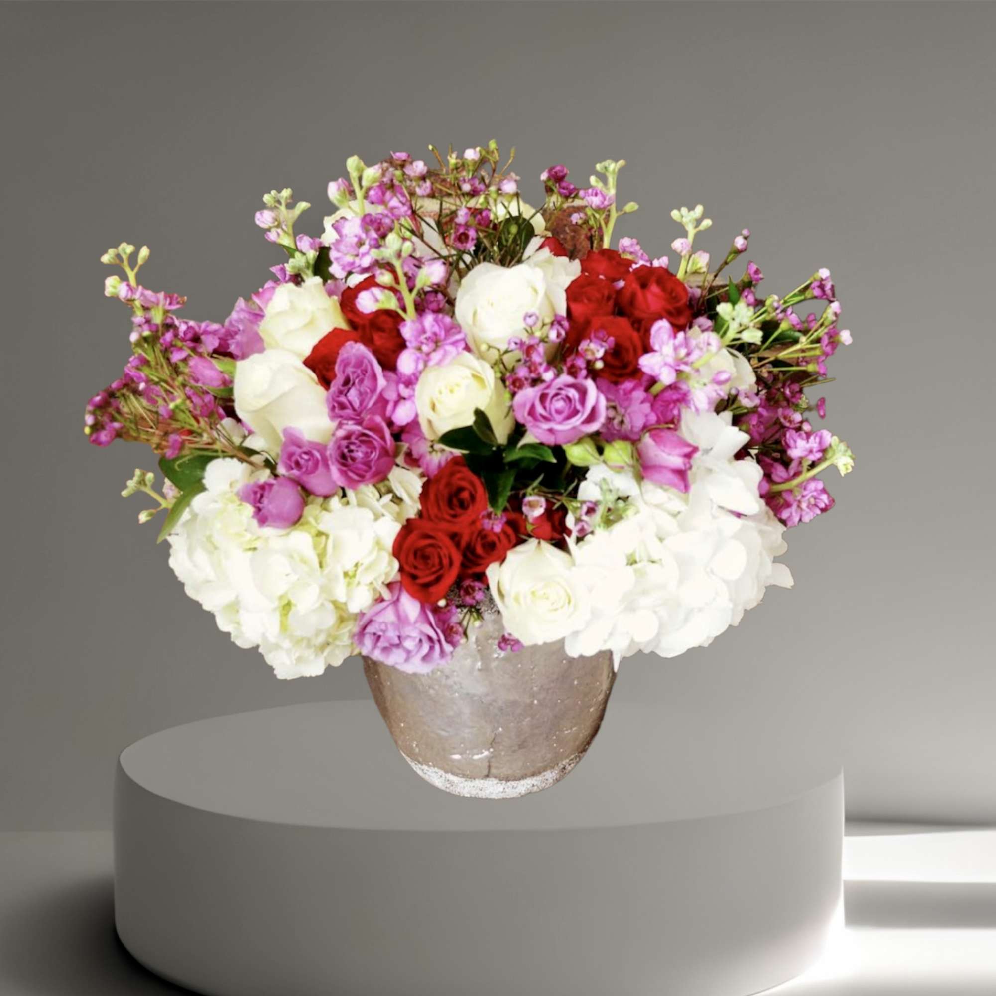 A beautiful mix of purple and red roses, hydrangea, and orchids in