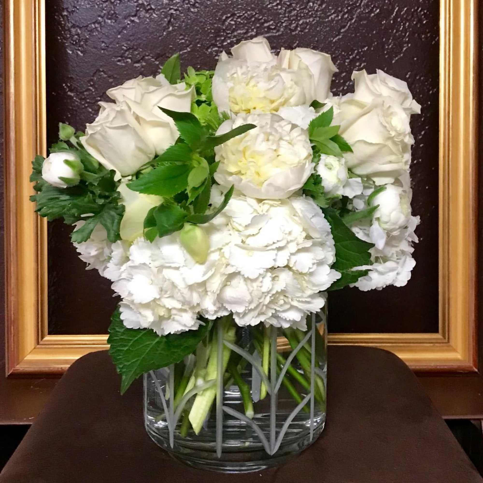 A mix of white roses, hydrangea, orchids and other seasonal white flowers