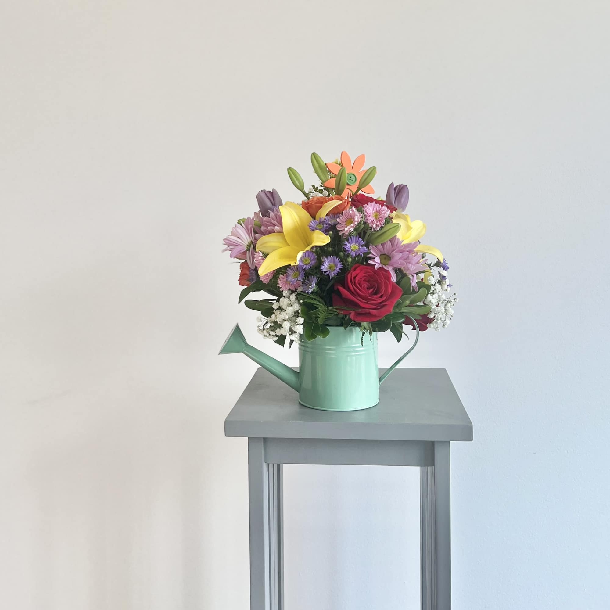 This unique summer bouquet comes in assorted color watering cans with fresh