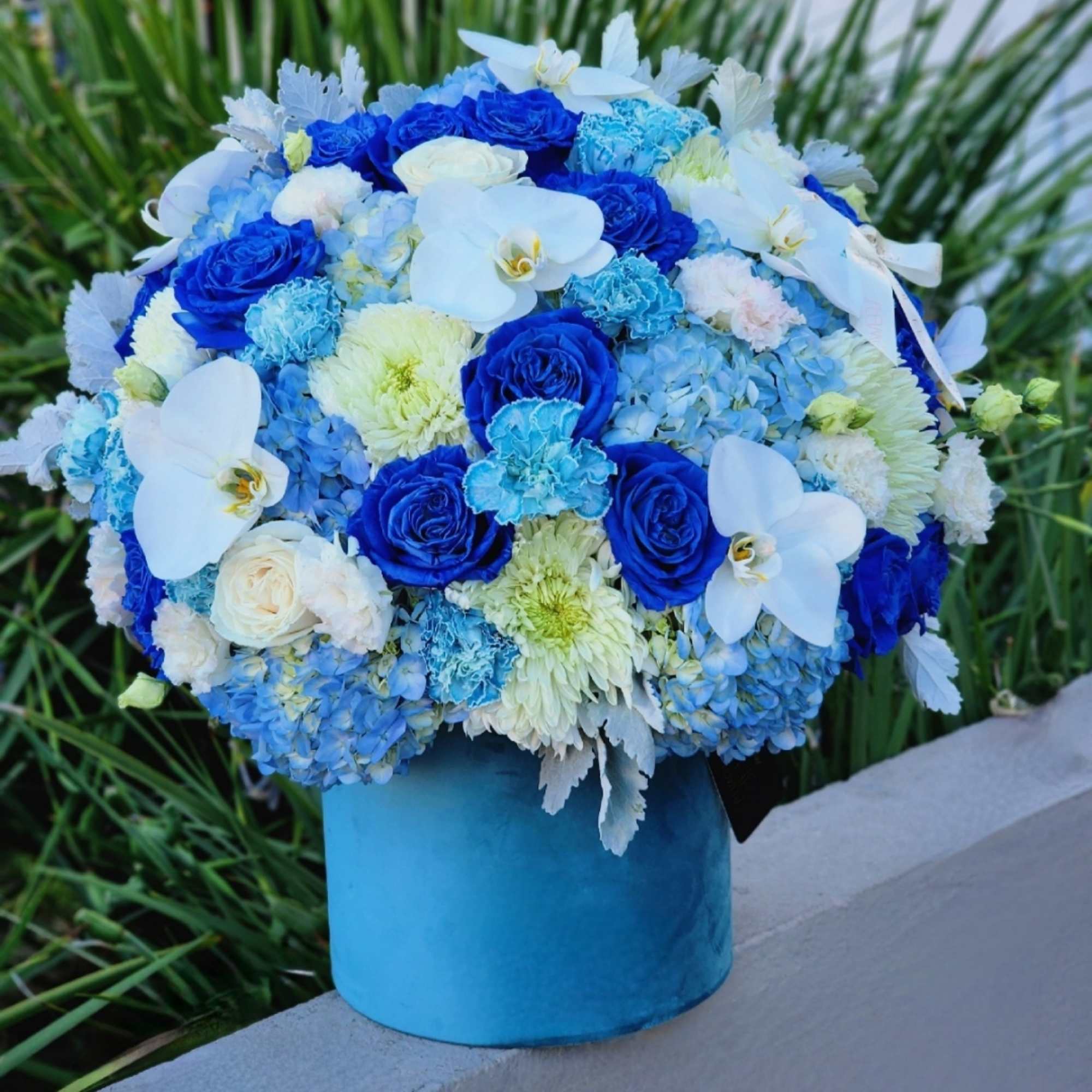 This blue-themed floral arrangement with blue hydrangeas, roses, and carnations, complemented by