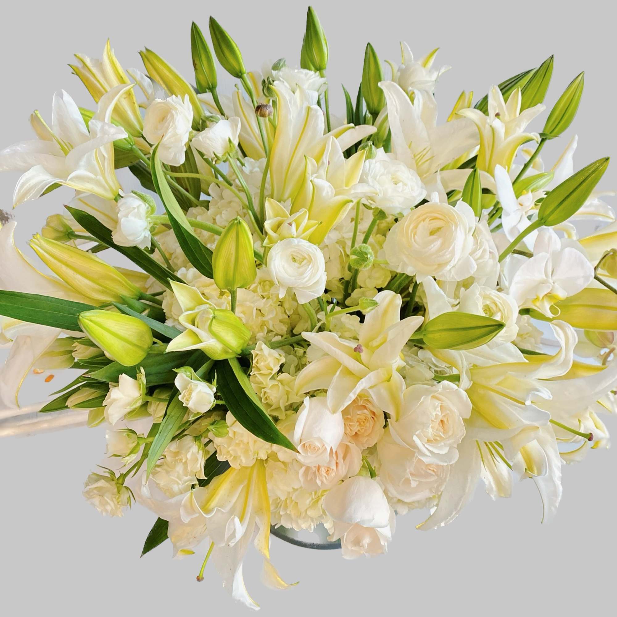 White lilies ,roses and white blooms stand tall and beautiful. Send an