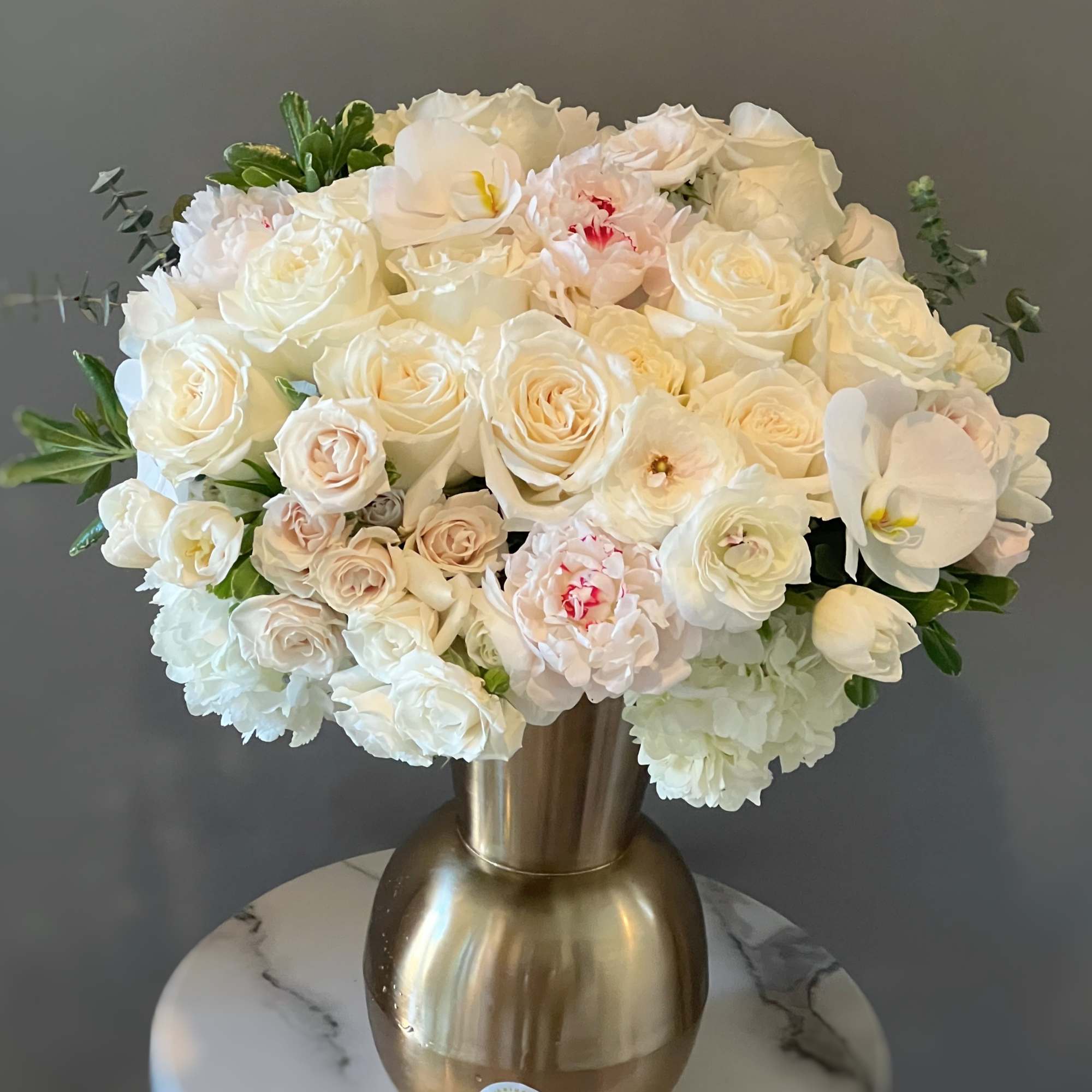 This petite all-white arrangement featuring roses,hydrangeas,peonies and seasonal blooms is the perfect