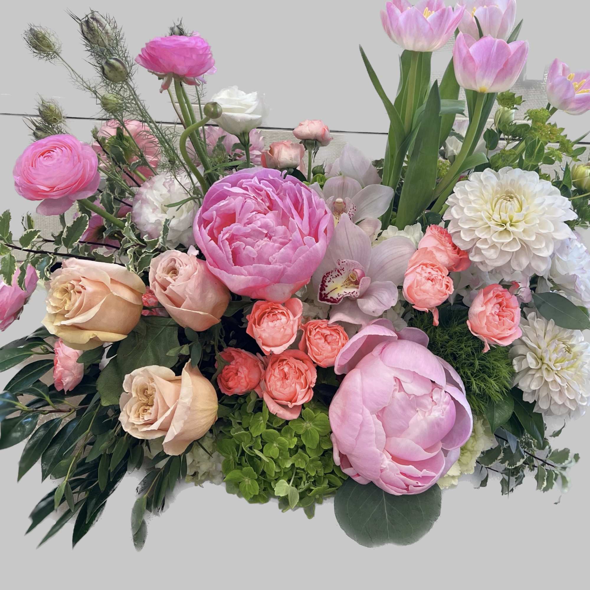 A bush like arrangement, has roses, tulips, peonies, and ranunculus. All very