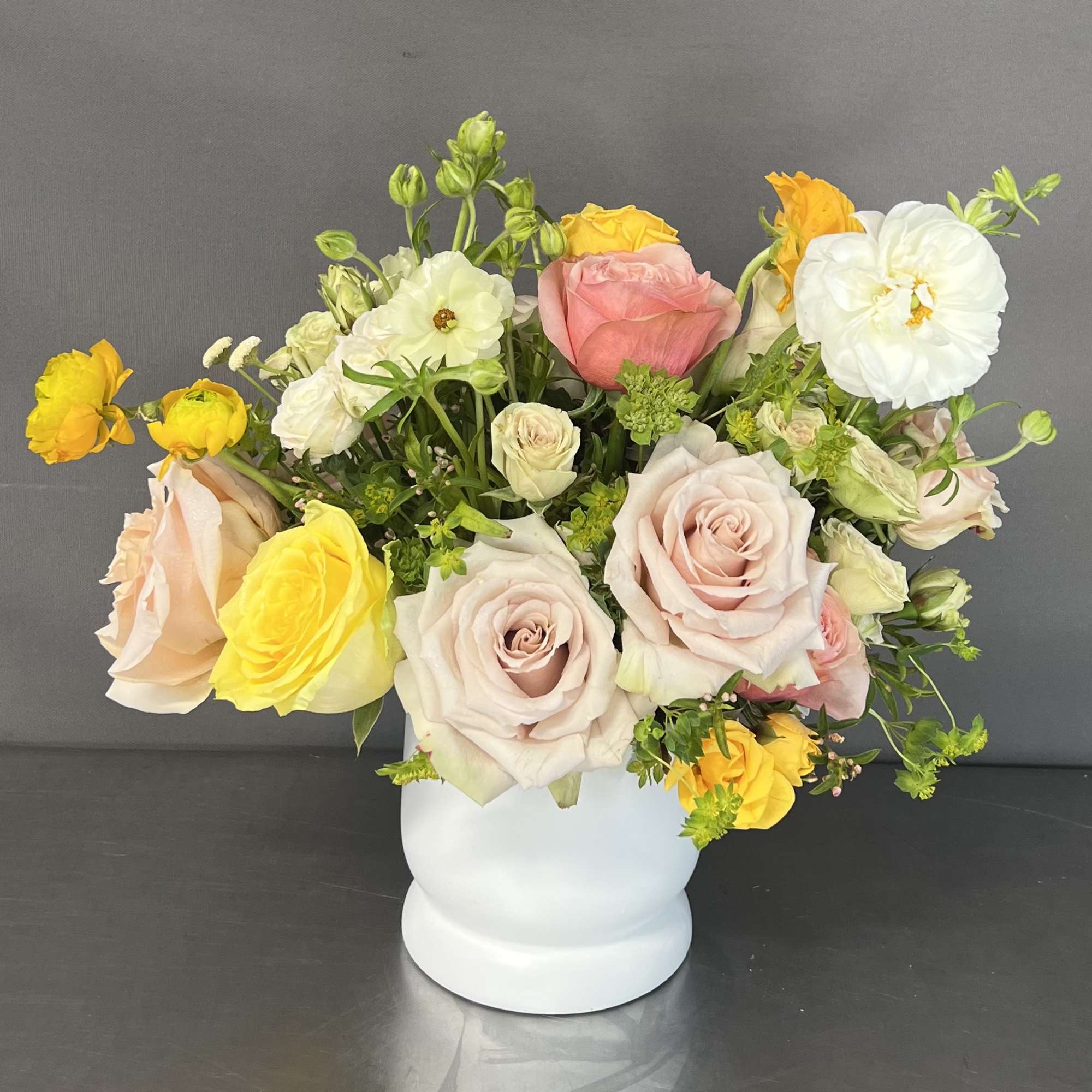 This delicate floral design is arranged in a white ceramic vase. This
